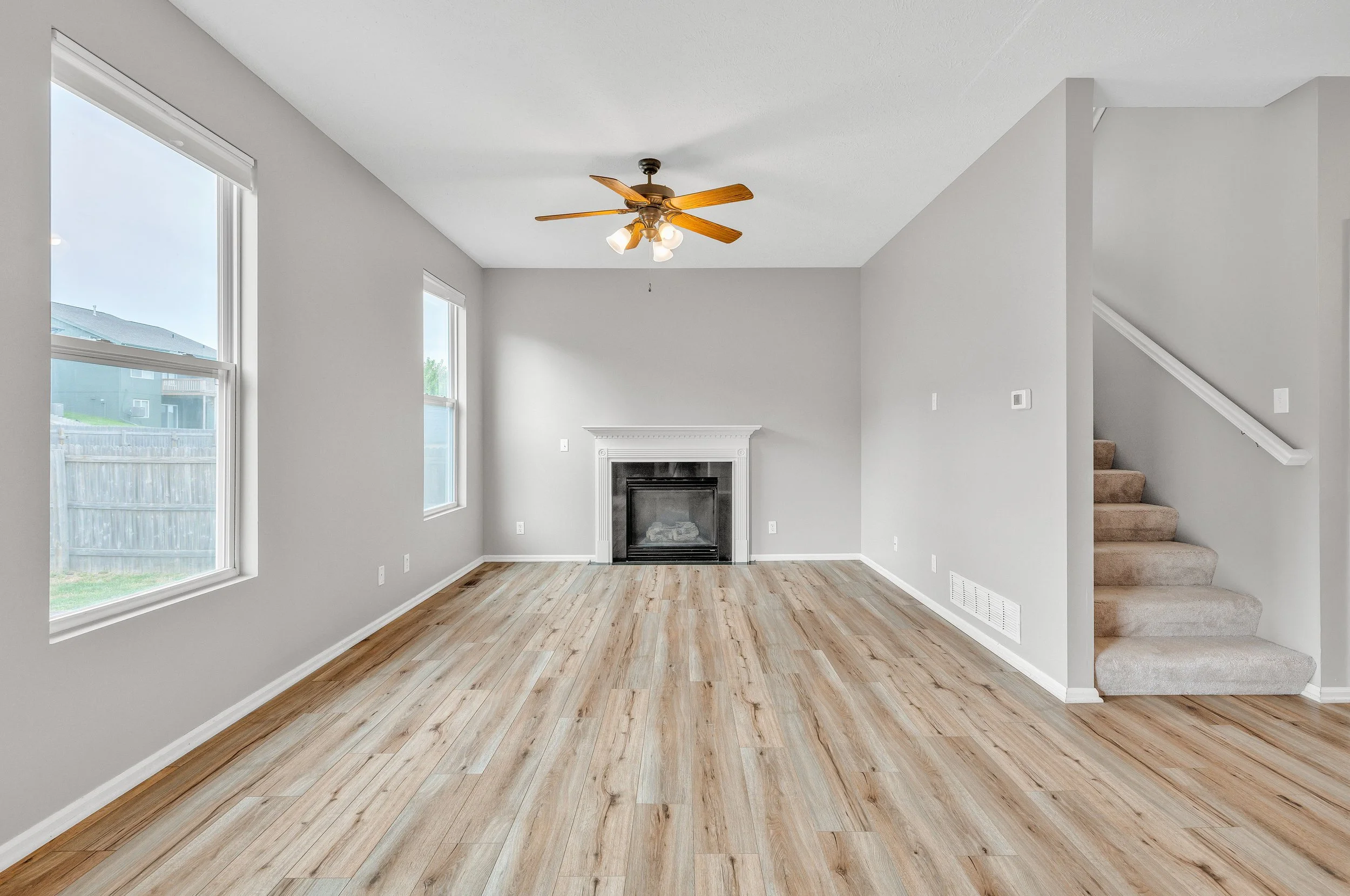 Vacant living room with fireplace, vaulted ceiling, and large windows showing clean HDR interior photography before virtual staging
