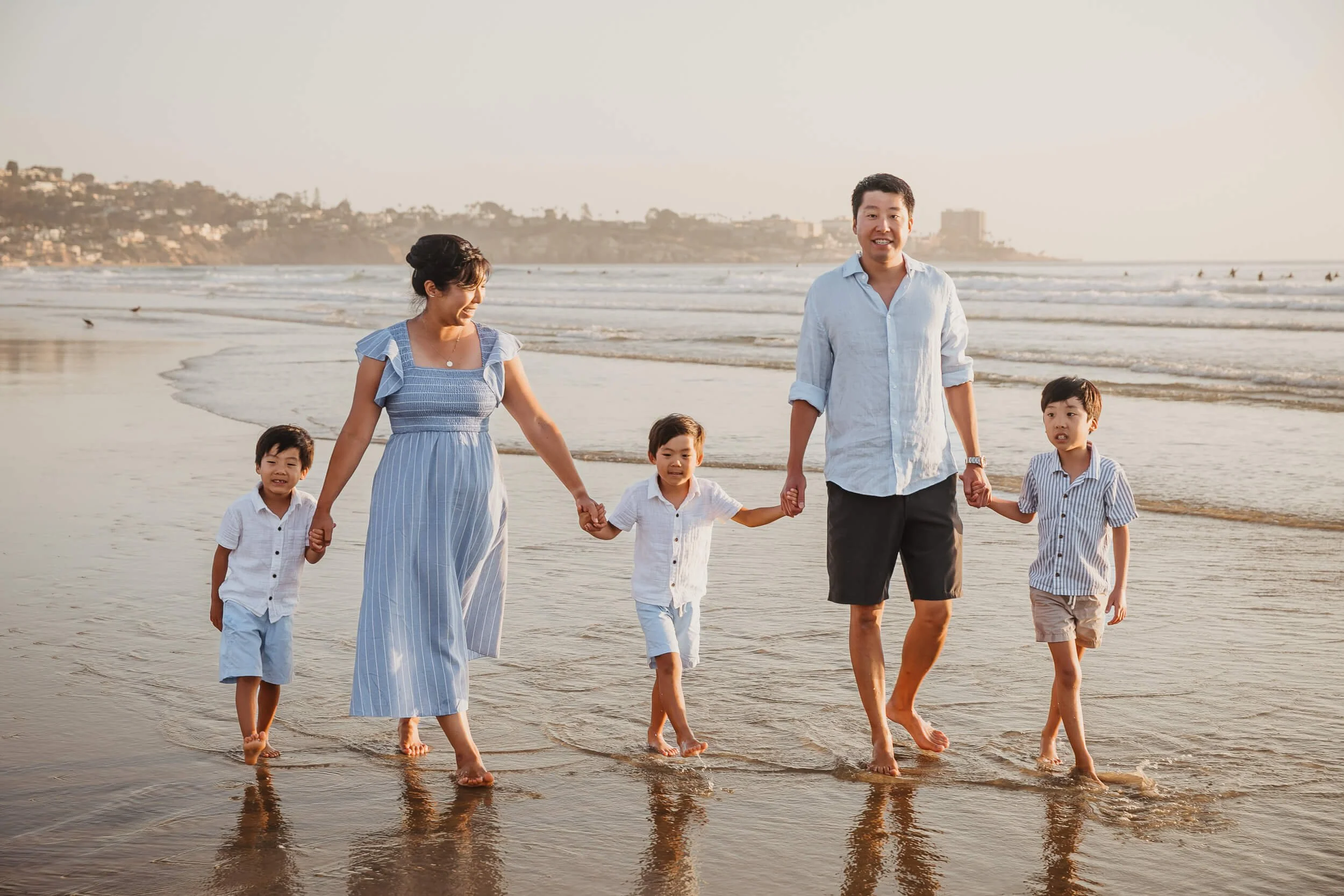Closeup family of five walking along waterline light color outfits during La Jolla Shores and Scripps Pier Family Photography in San Diego