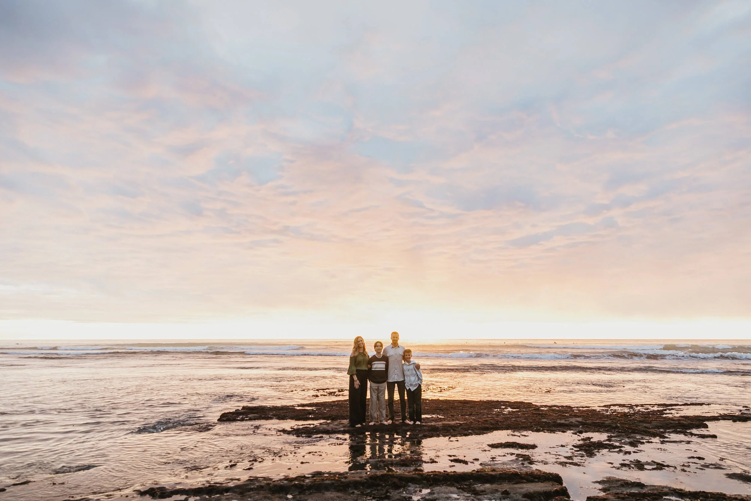 Family standing on tide pools during sunset in Southern California