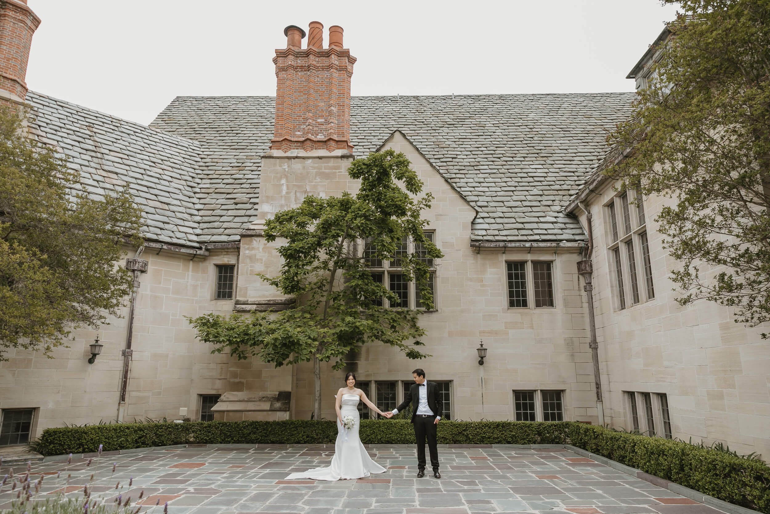 couple holding hands in front of Greystone Mansion and Gardens Engagement Photos Beverly Hills English Tudor Revival architecture