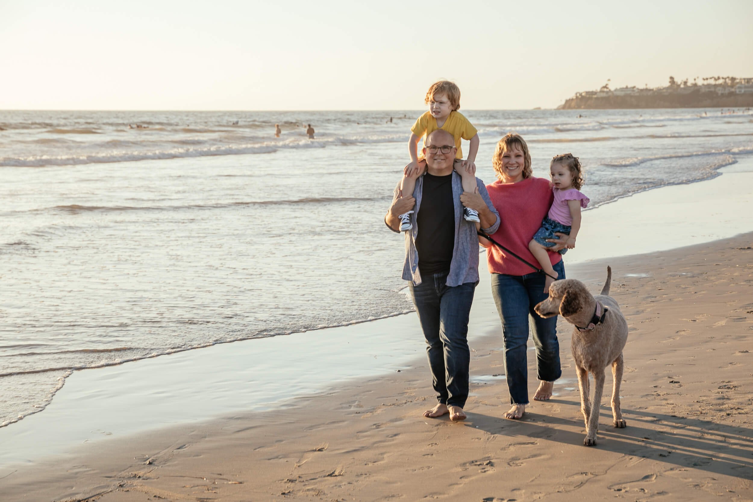 Pacific Beach / Crystal Pier Family Sessions mom, dad, children and dog walking along shoreline looking at photographer