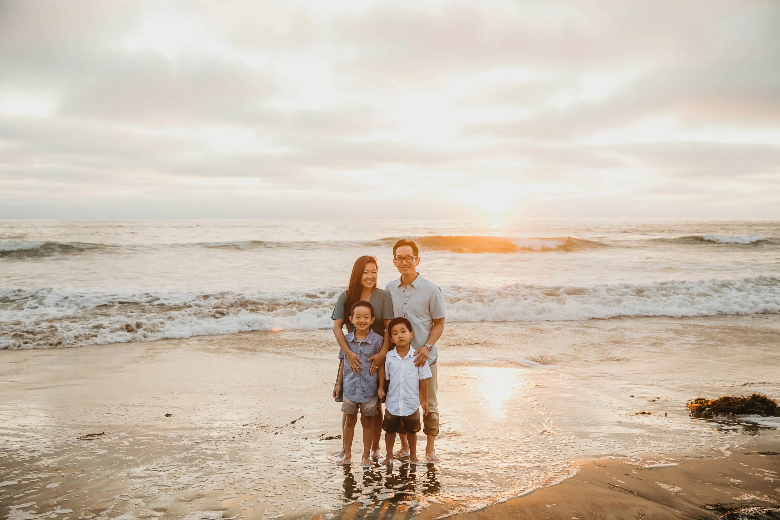 Amazing sunset light for photo of mom and dad and two boys during golden hour at La Jolla Shores and Scripps Pier Family Photography in San Diego