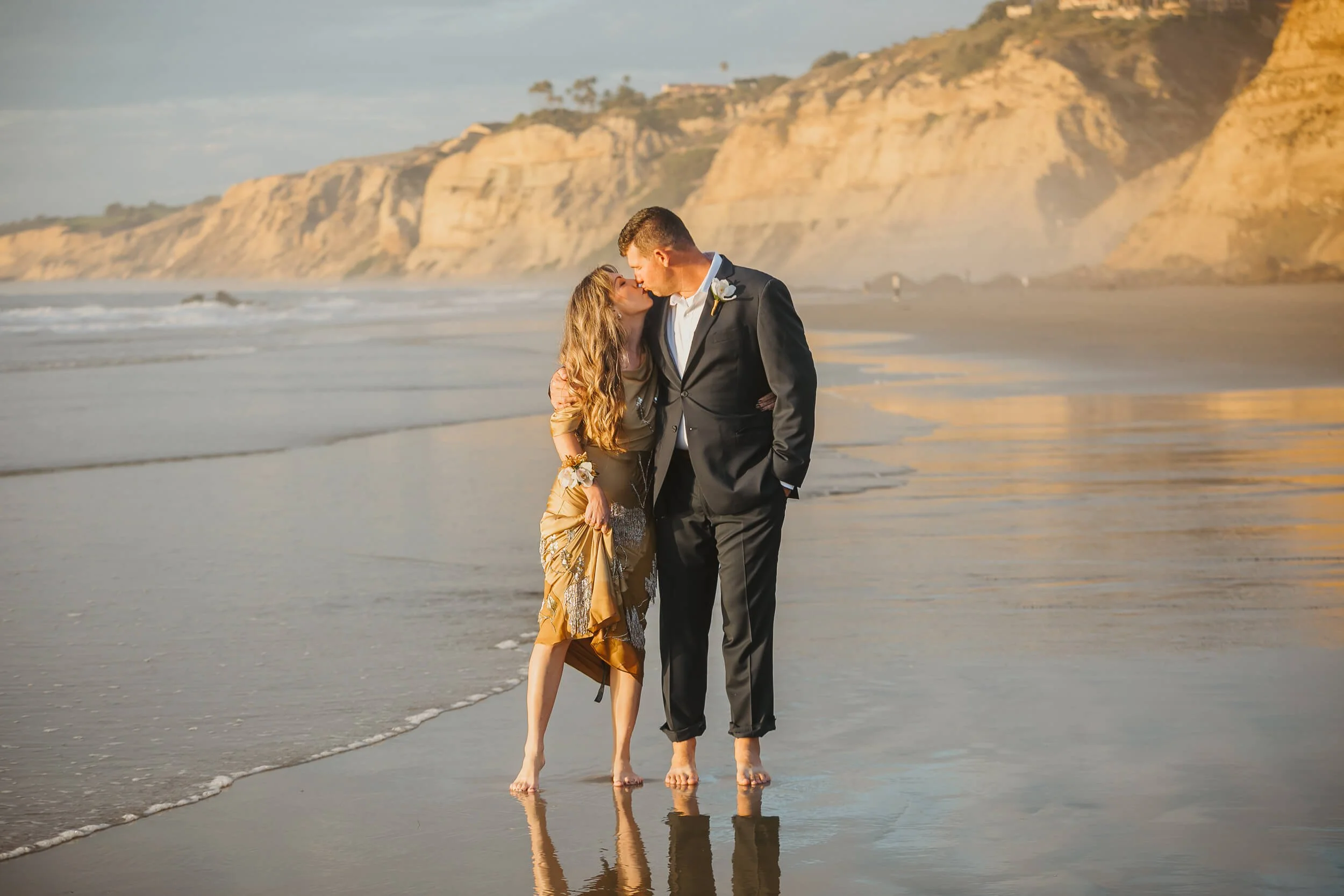 Couple kissing close to the ocean with Blacks beach cliff behind for La Jolla Shores and Scripps Pier Family Photography in San Diego