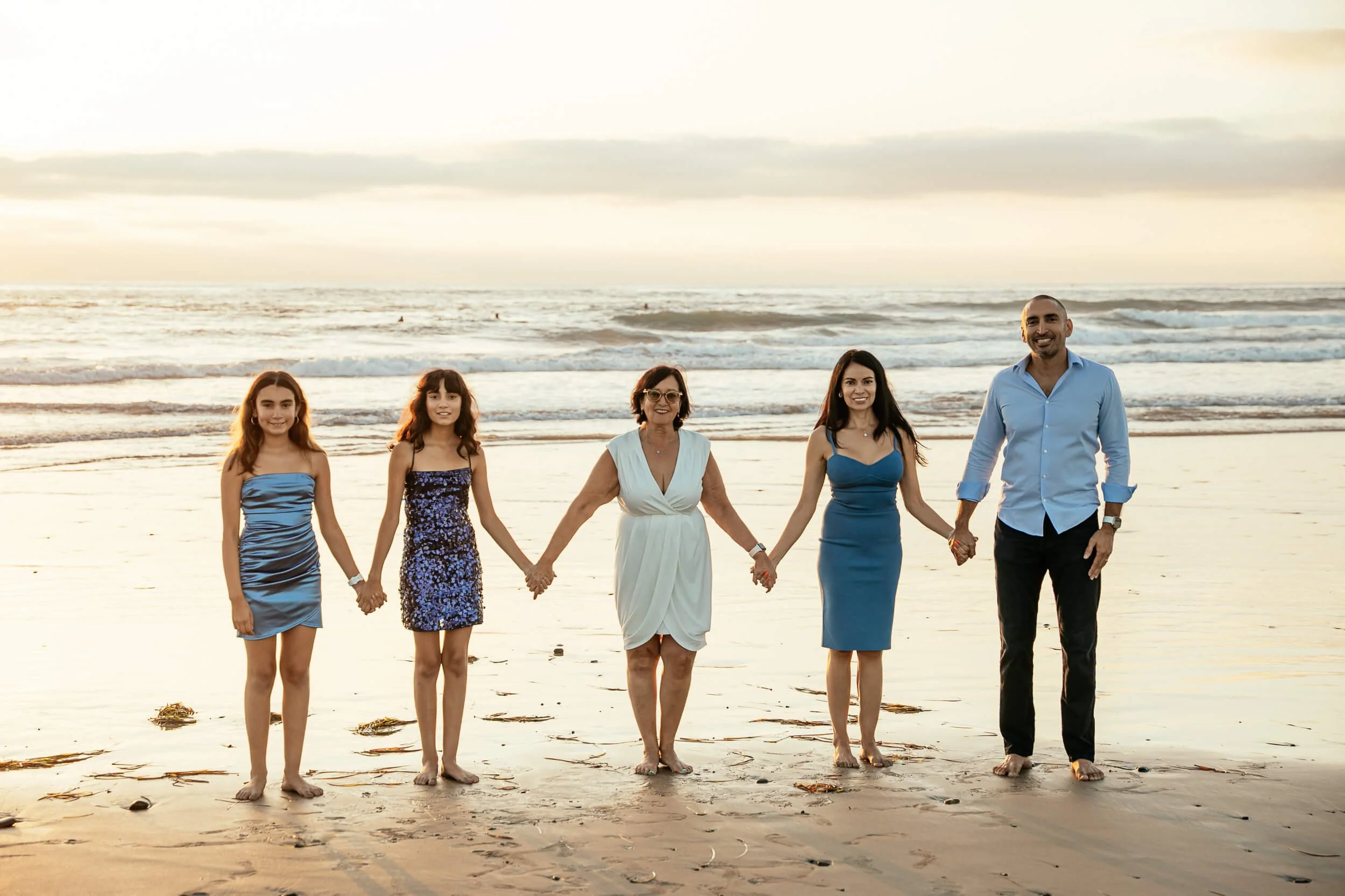 Family holding hands at the beach during a Carlsbad Beach Family Photography Session at sunset