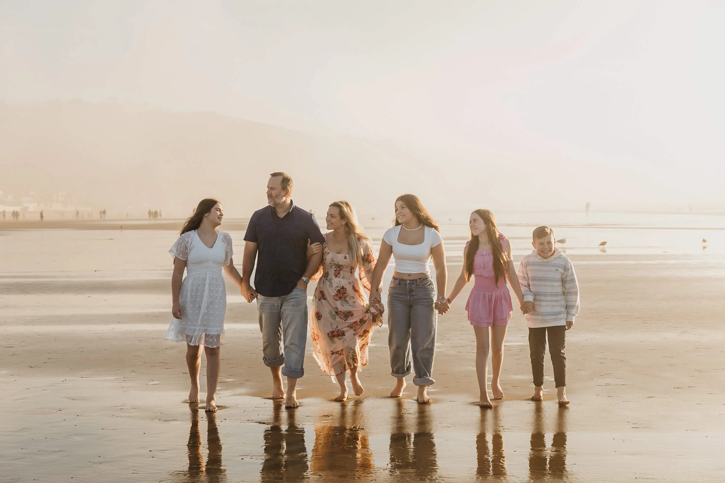 Family of six casually walking on shoreline looking at each other and talking during La Jolla Shores and Scripps Pier Family Photography in San Diego