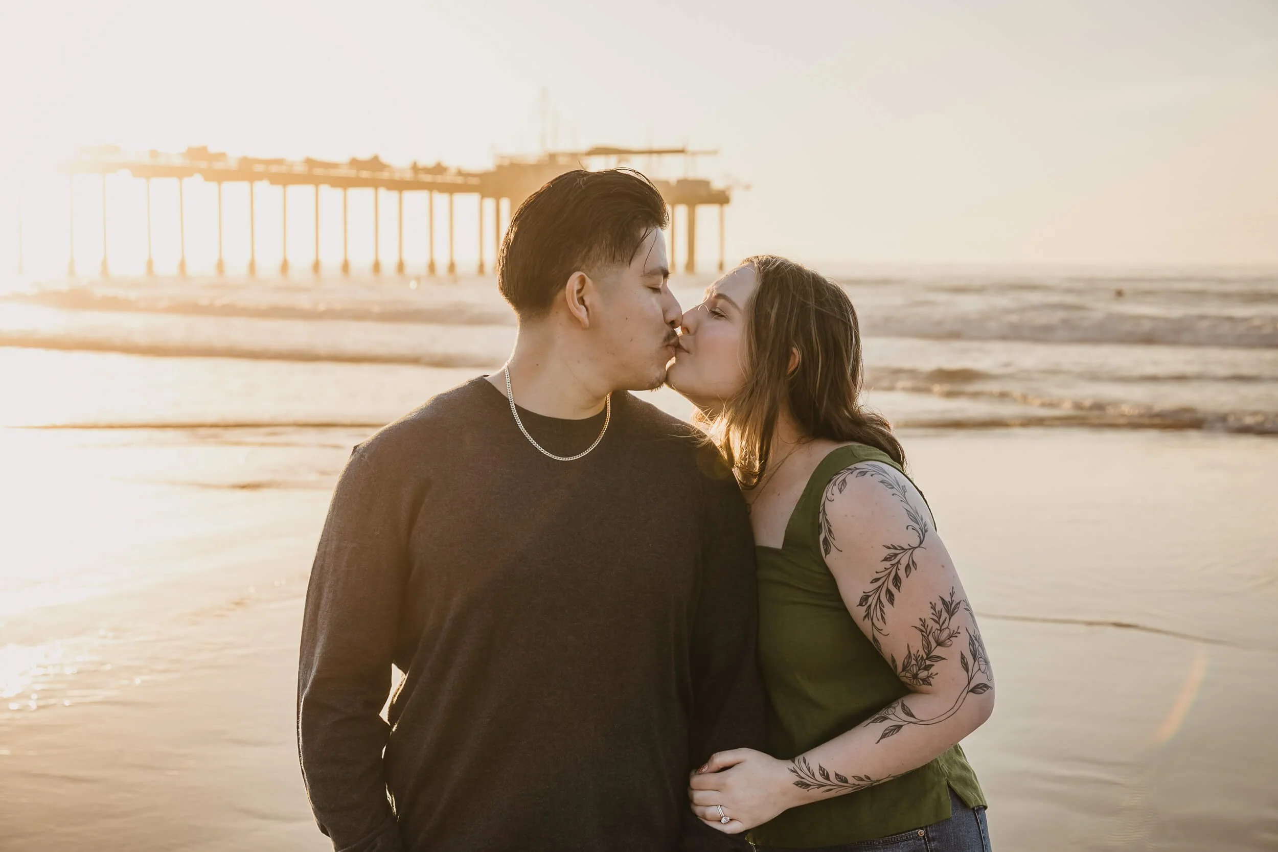 Couple kissing with Scripps Pier in background at La Jolla Shores engagement portrait session