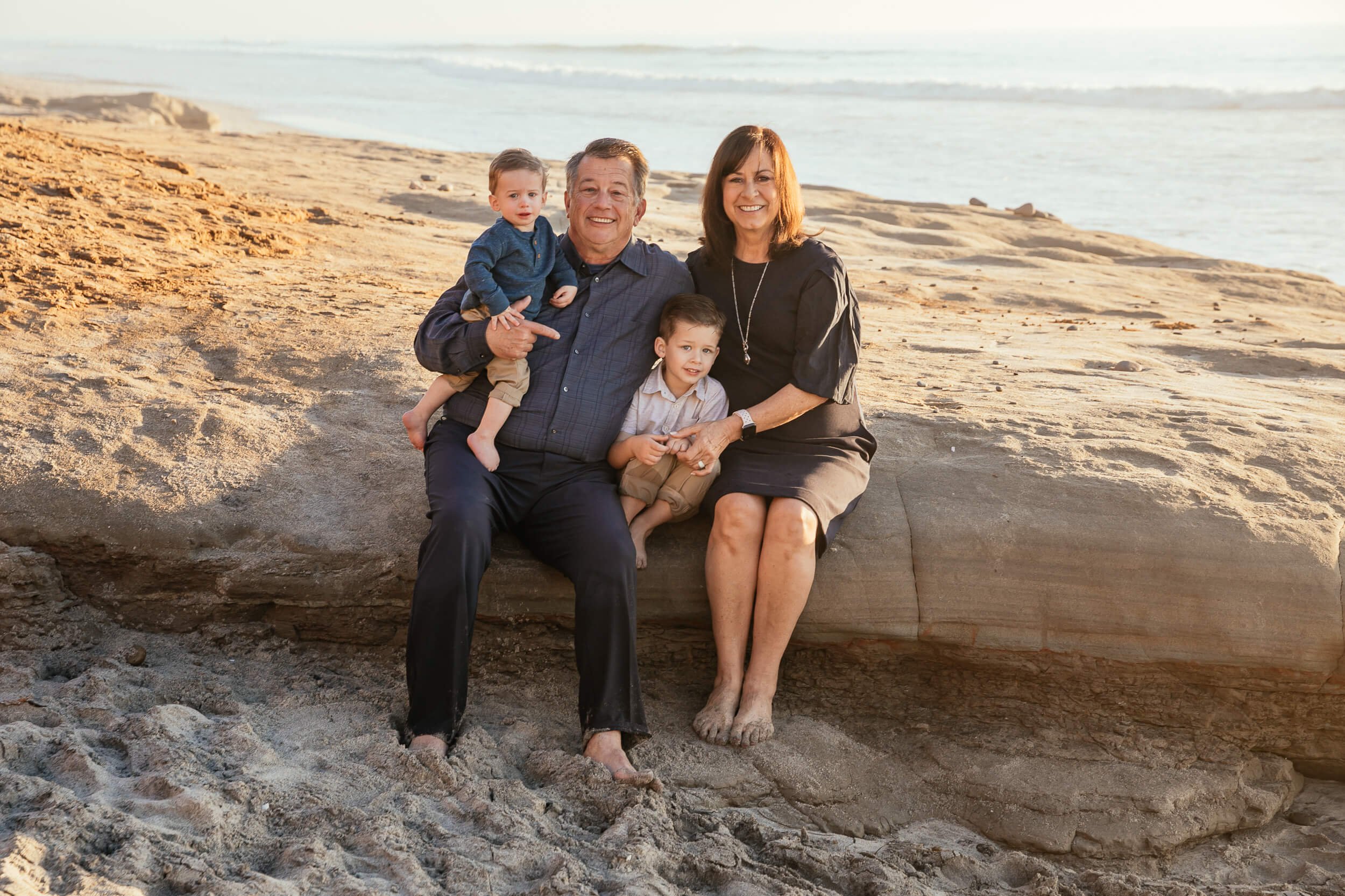 Family portrait sitting on driftwood during a sunset Carlsbad Beach Family Photography Session