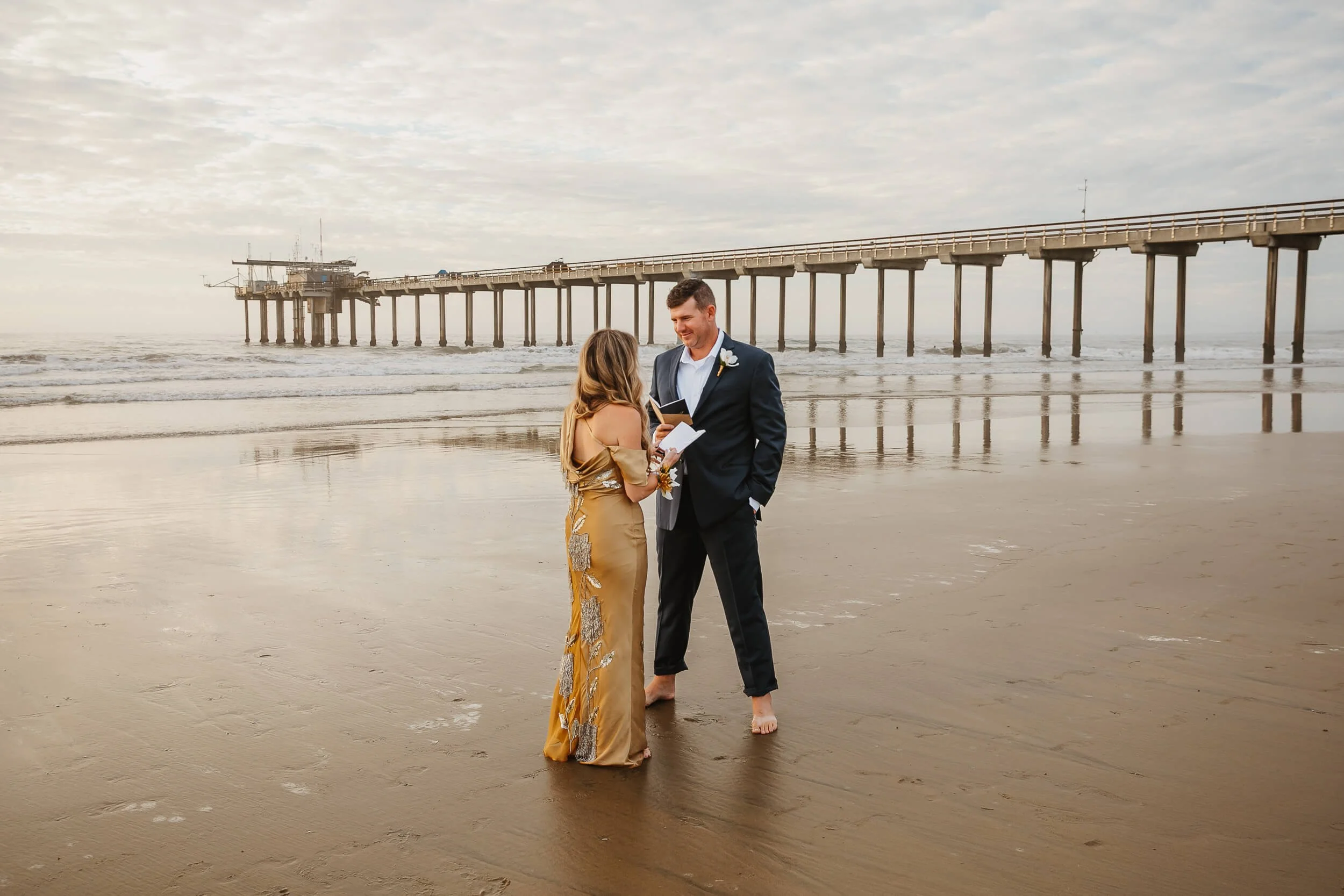 Woman reading vows to husband during wedding anniversary photo session in La Jolla Shores and Scripps Pier Family Photography in San Diego