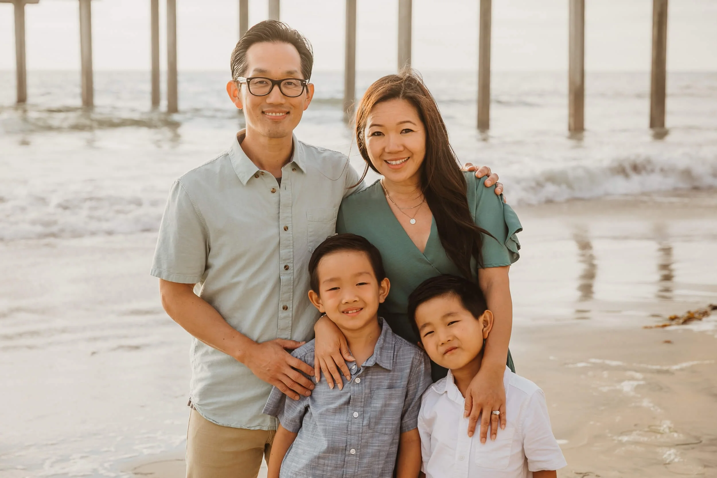 Closeup family of four looking at camera and smiling for La Jolla Shores and Scripps Pier Family Photography in San Diego