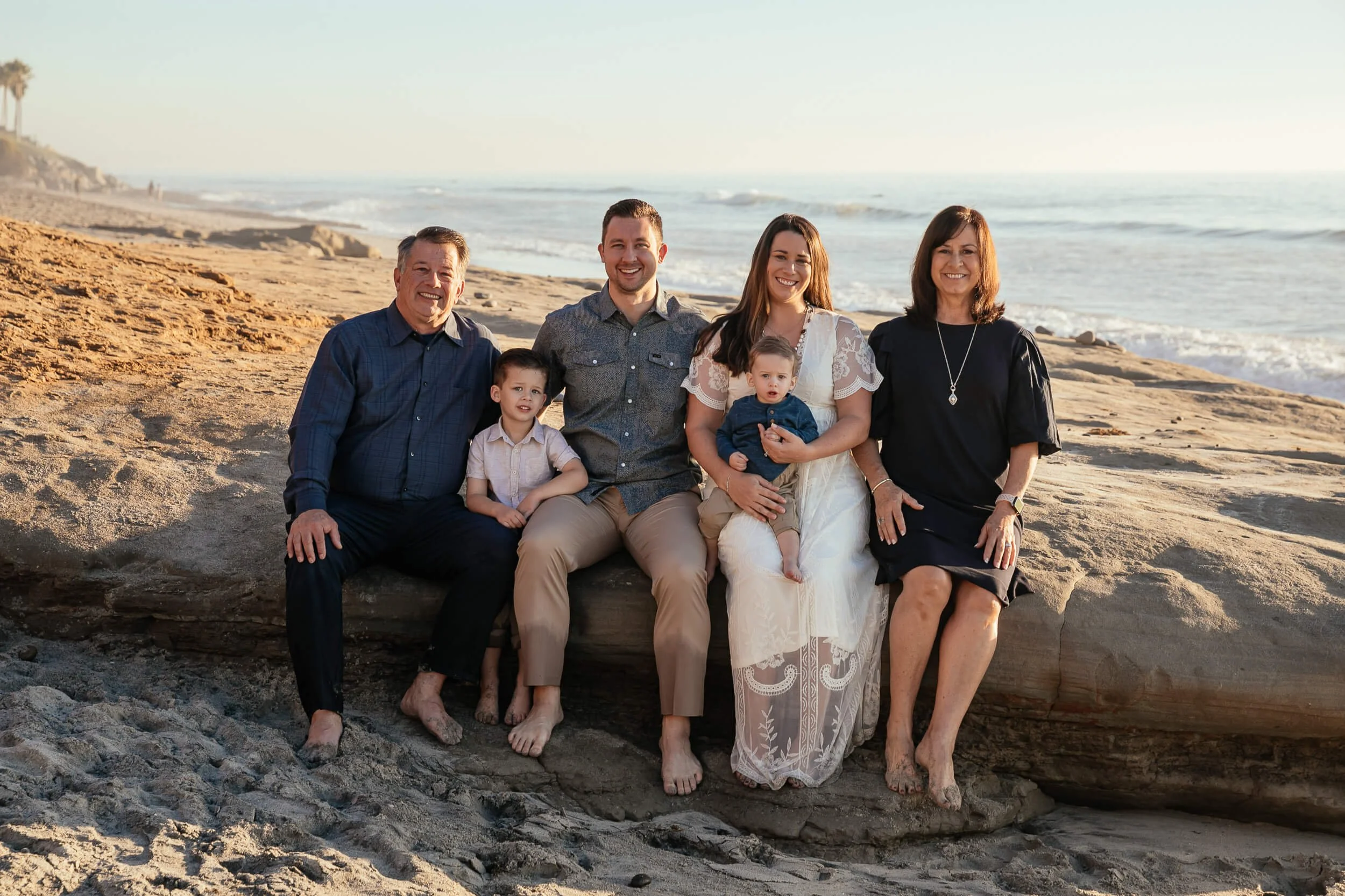 Family portrait sitting together on driftwood during a Carlsbad Beach Family Photography Session