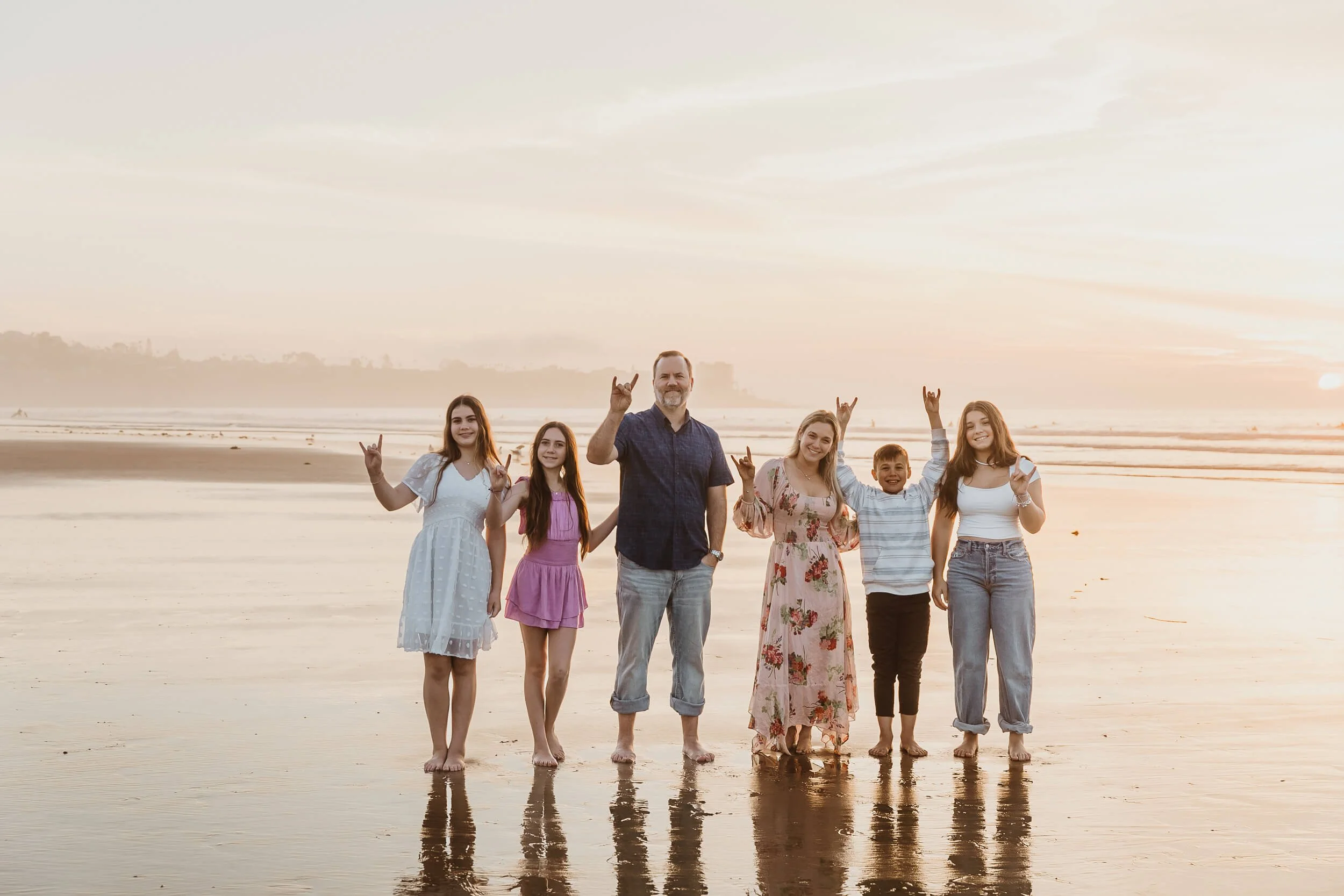 Fun photo of family doing the shaka and enjoying their portrait session at La Jolla Shores in San Diego beach 