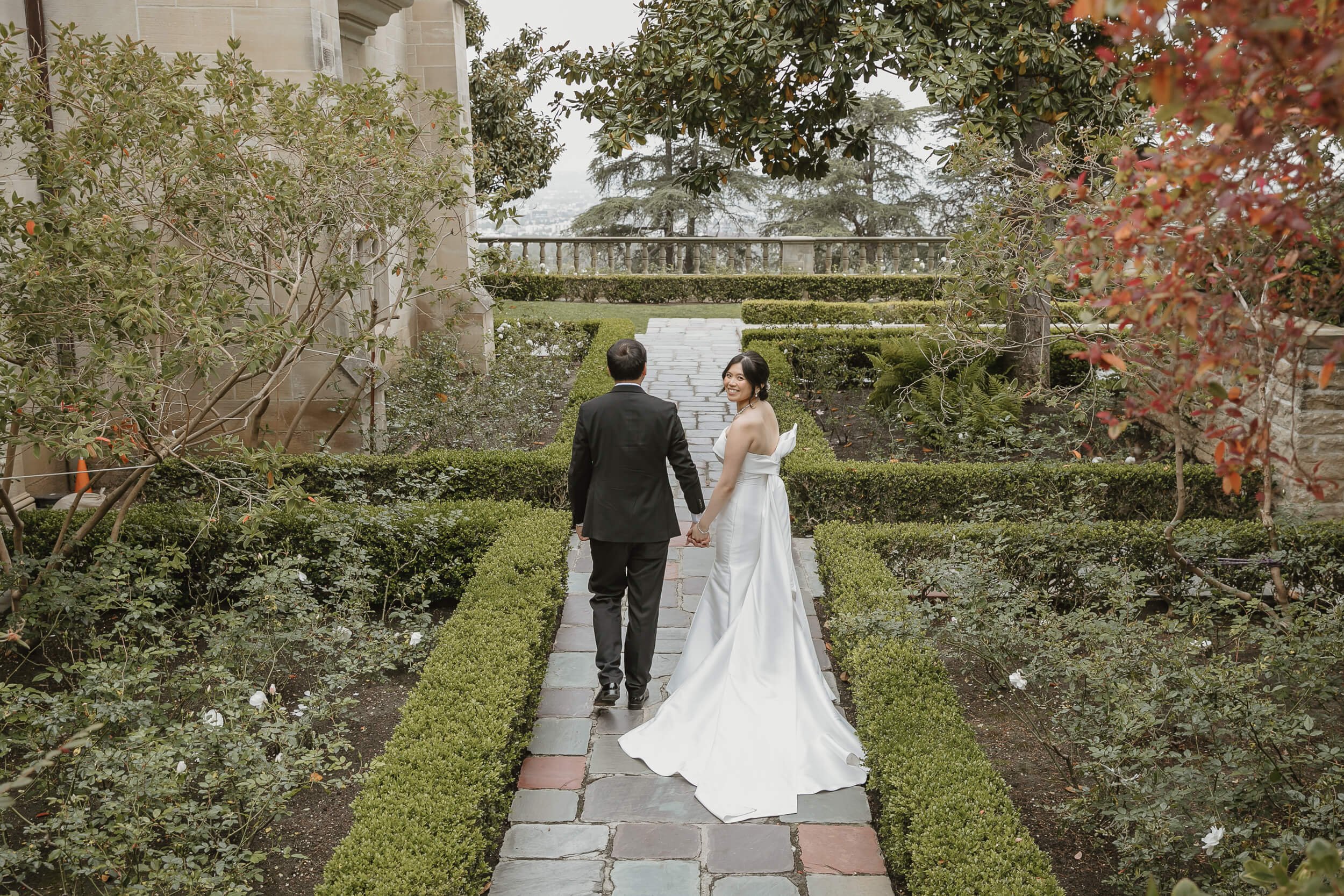 Bride looking over her shoulder while walking away at Greystone Mansion and Gardens Engagement Photos Beverly Hills