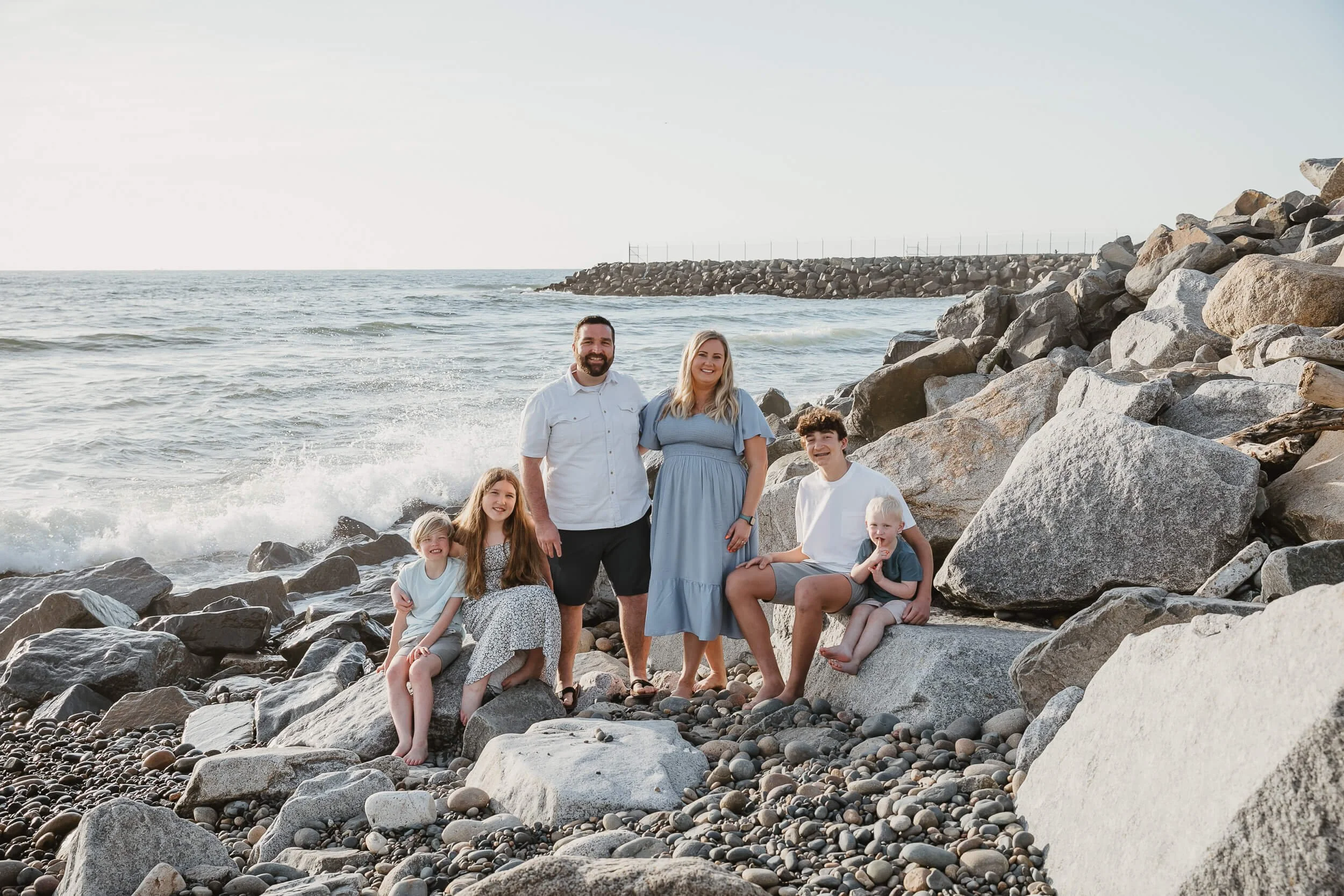 Family sitting on beach rocks during a Carlsbad Beach Family Photography Session at sunset