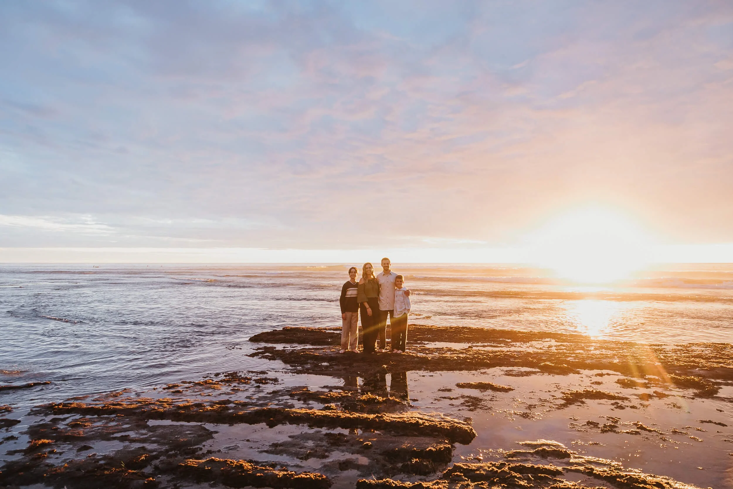 Wide sunset family portrait during a Carlsbad Beach Family Photography Session by the ocean