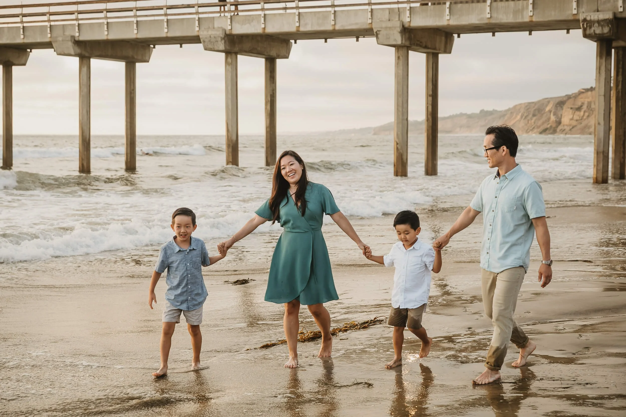 Smily family walking along shoreline during La Jolla Shores and Scripps Pier Family Photography in San Diego