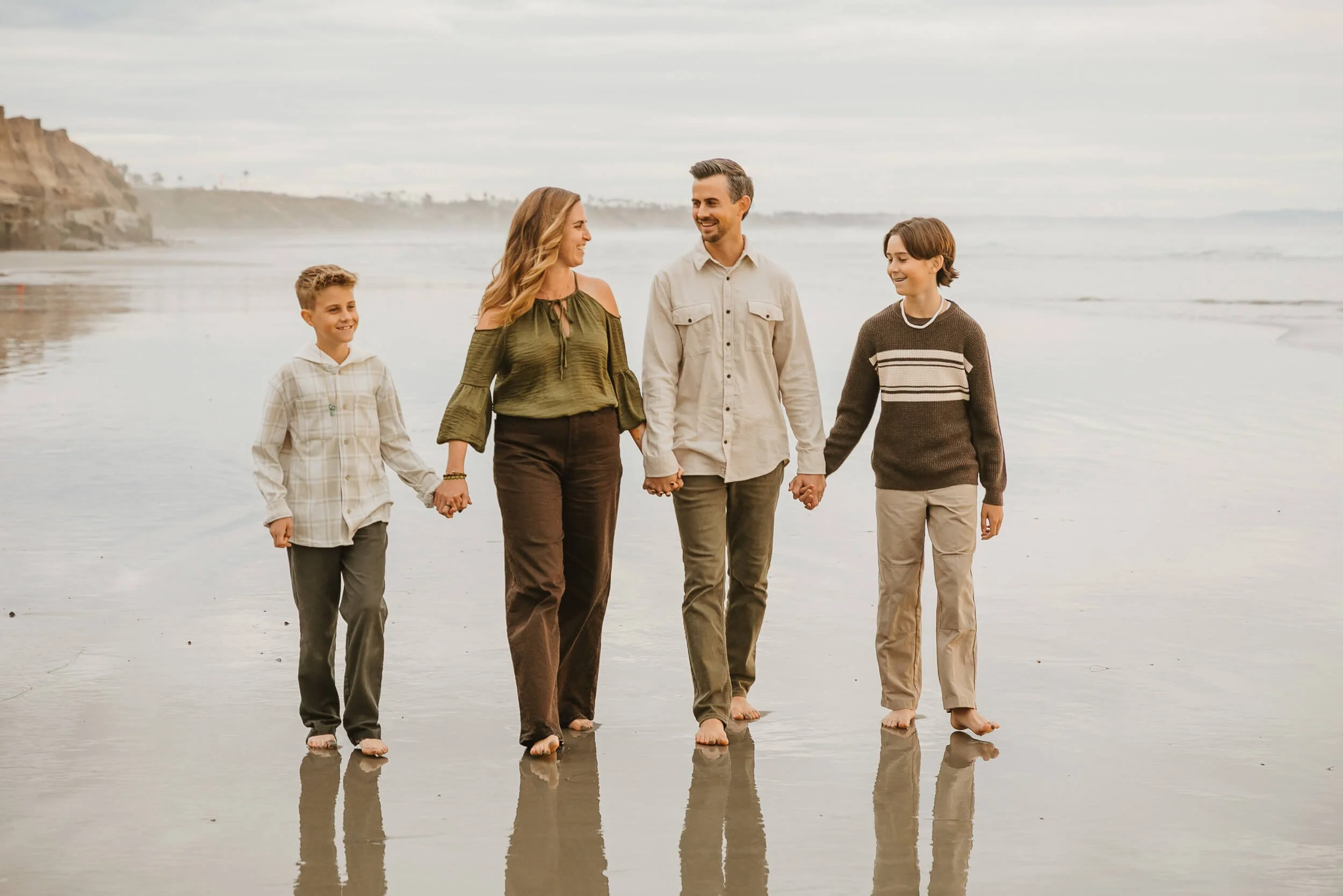 Family walking together on the beach photographed by a Carlsbad wedding photographer
