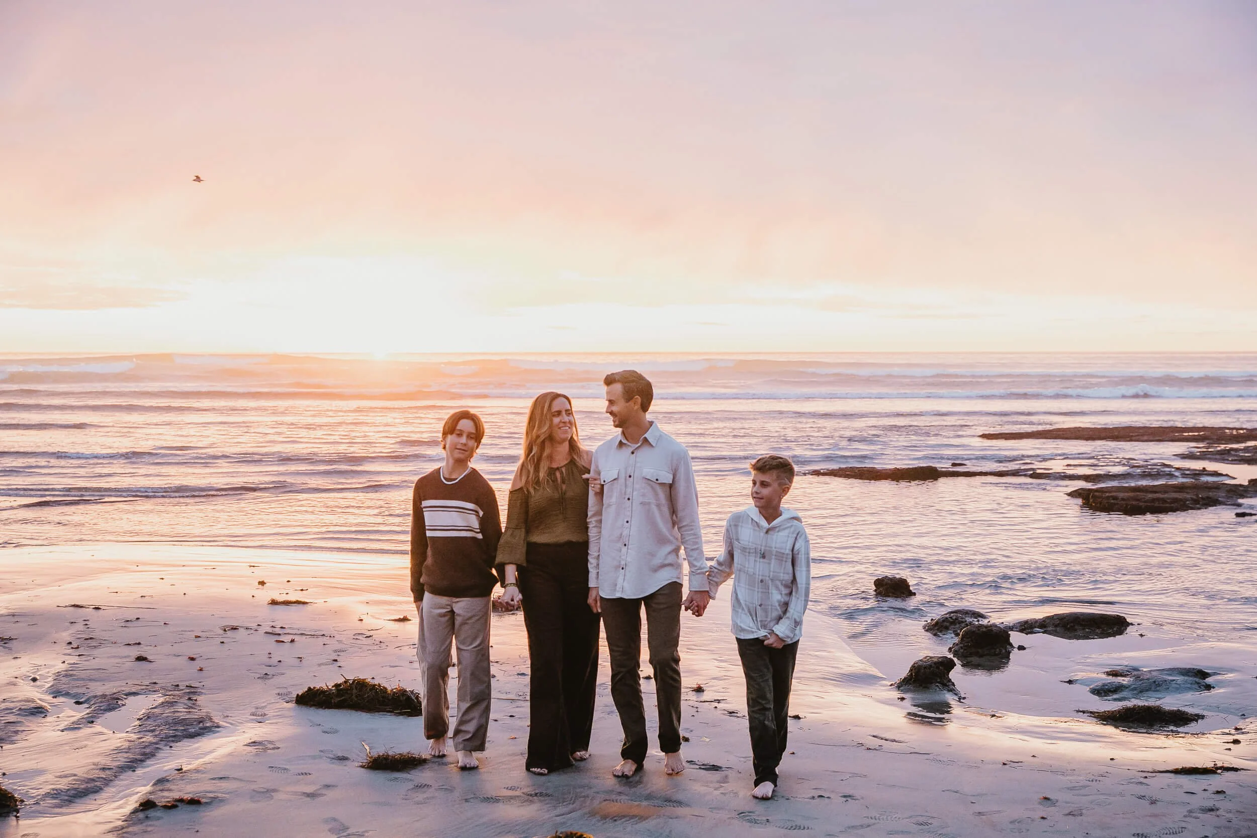 Family walking along tide pools during golden hour in Southern California