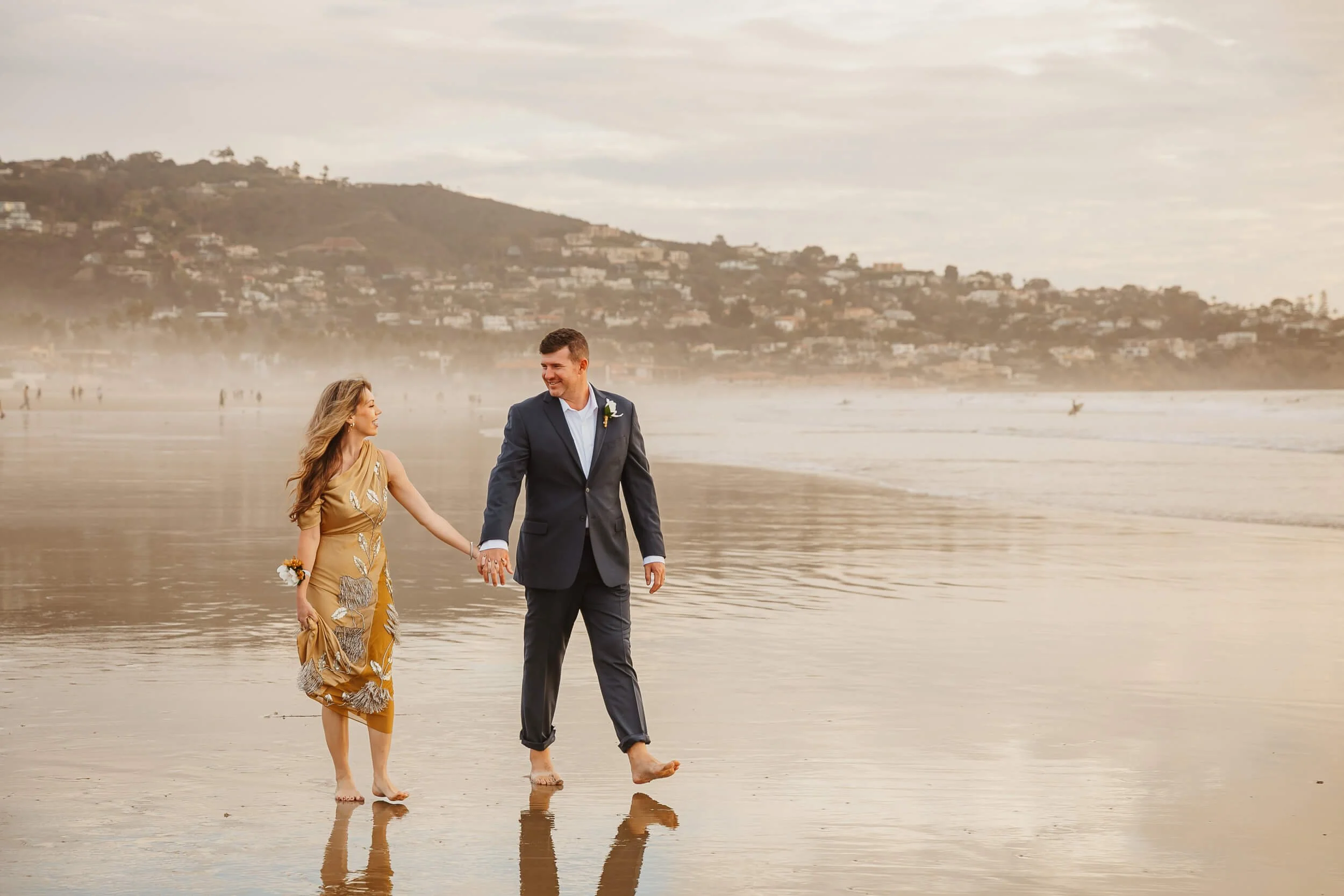 romantic shot couple looking at each other while walking on shoreline at La Jolla Shores Beach 