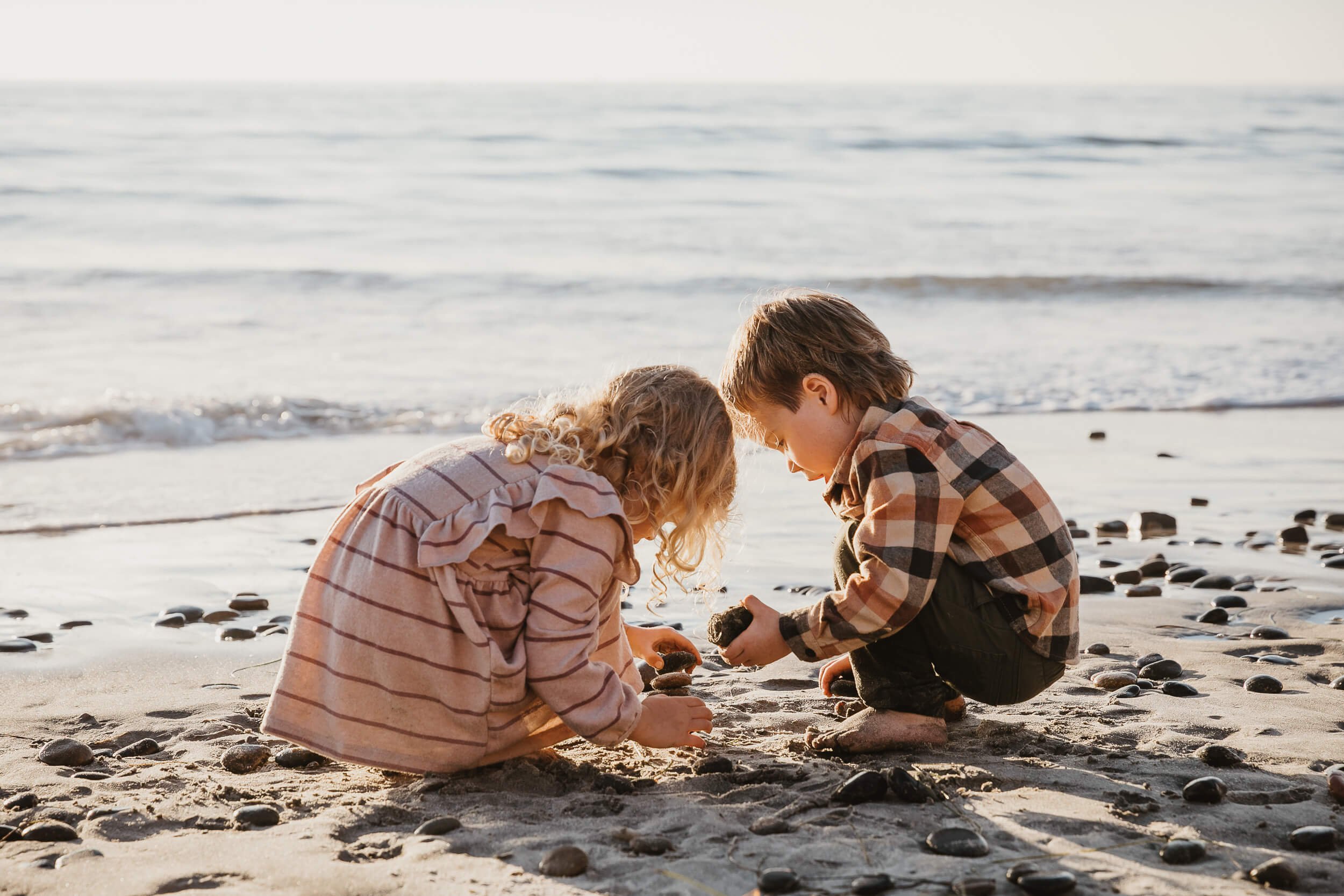 Children playing in the sand during a Carlsbad Beach Family Photography Session at sunset