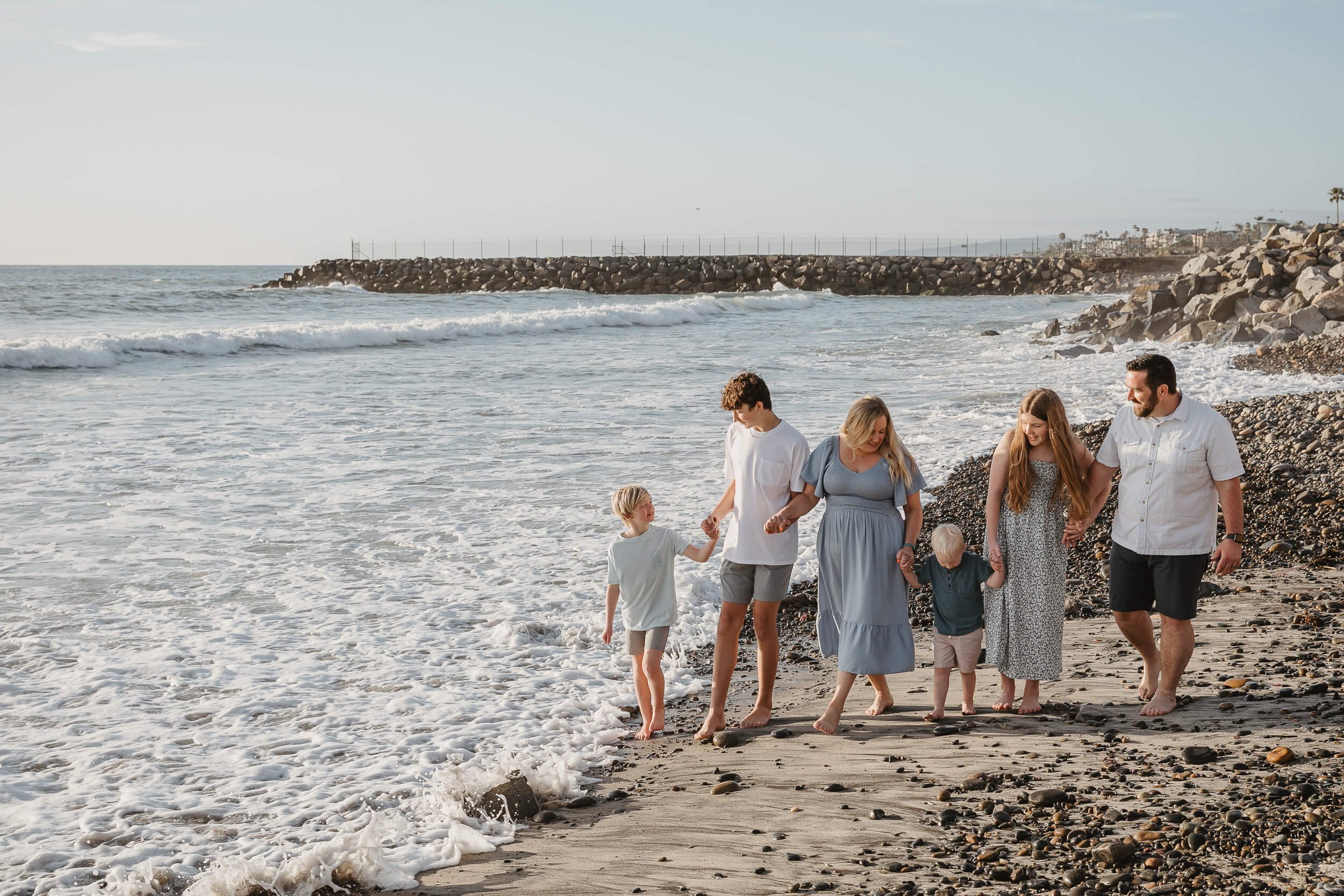 Family walking along the shoreline during golden hour in Carlsbad, California