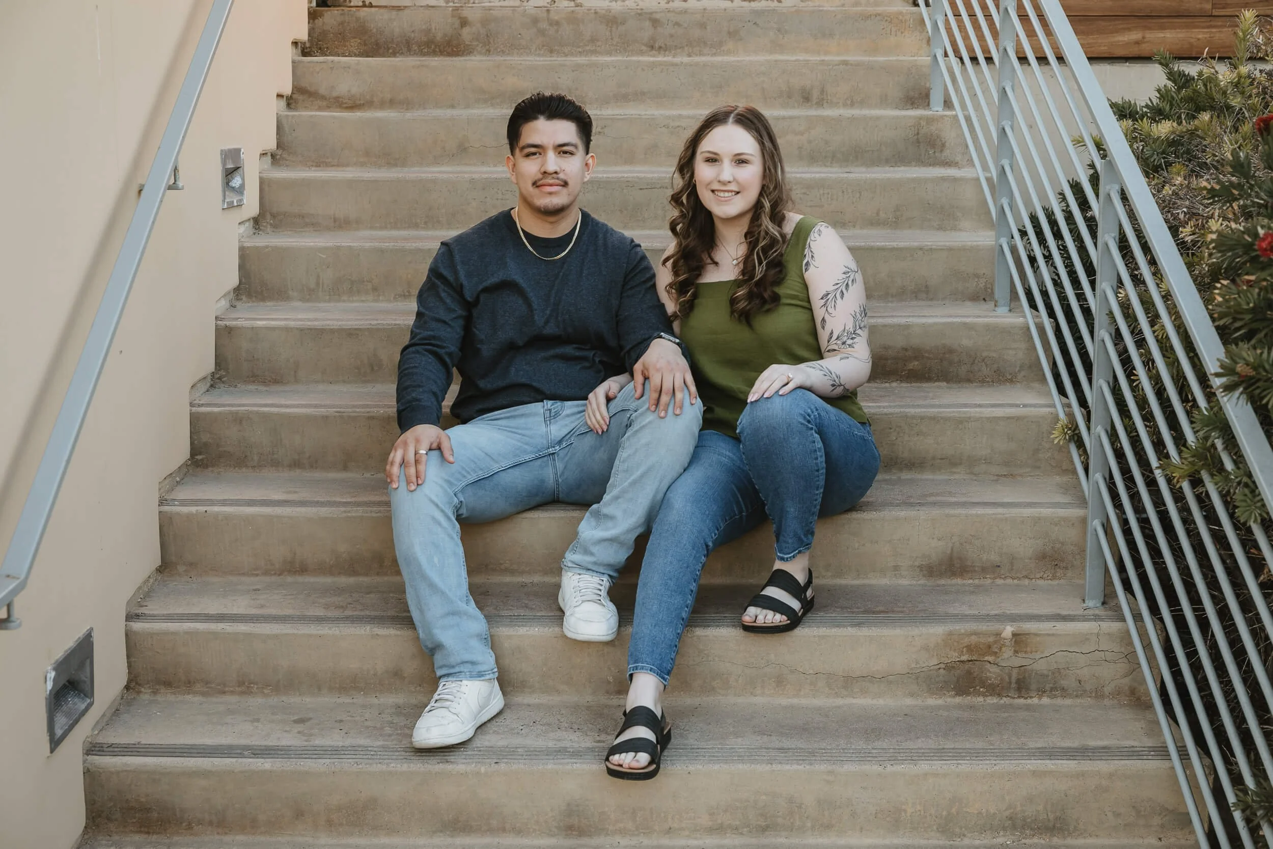 La Jolla Shores engagement session couple sitting on stairs together looking at camera 