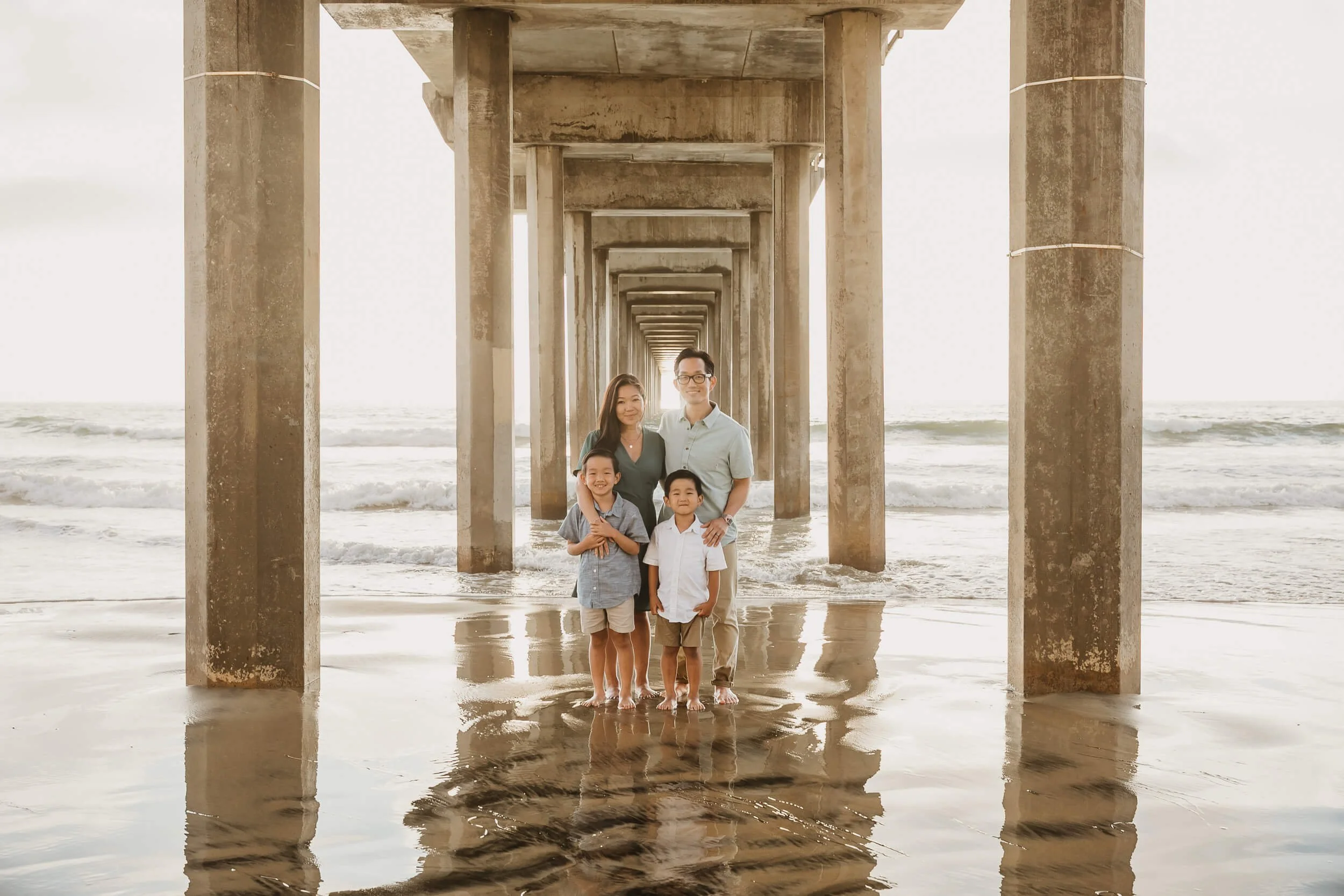 Family under symmetric Pier during La Jolla Shores and Scripps Pier Family Photography in San Diego