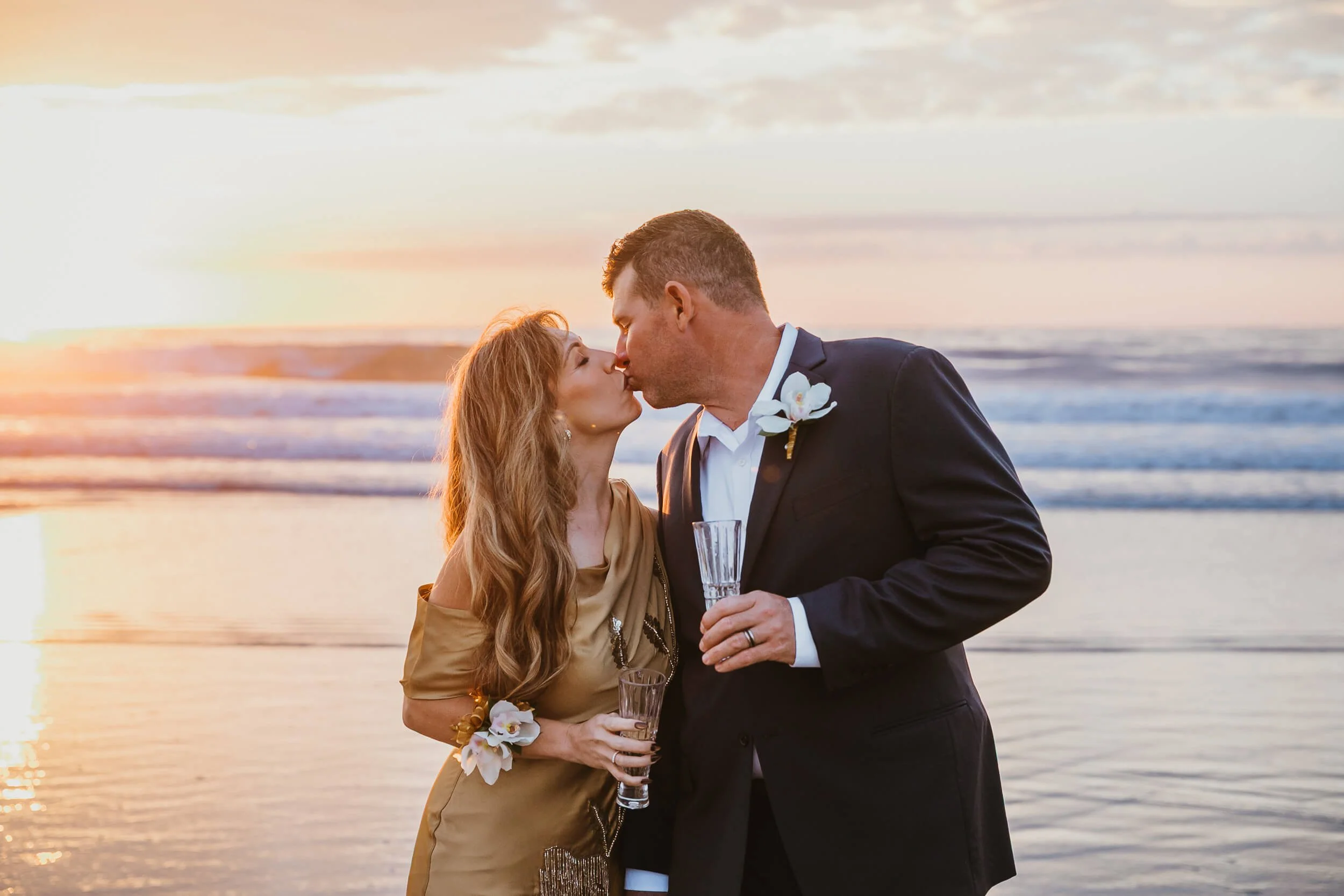 Closeup couple kissing and holding Champagne glasses at La Jolla Shores beach for San Diego family session 