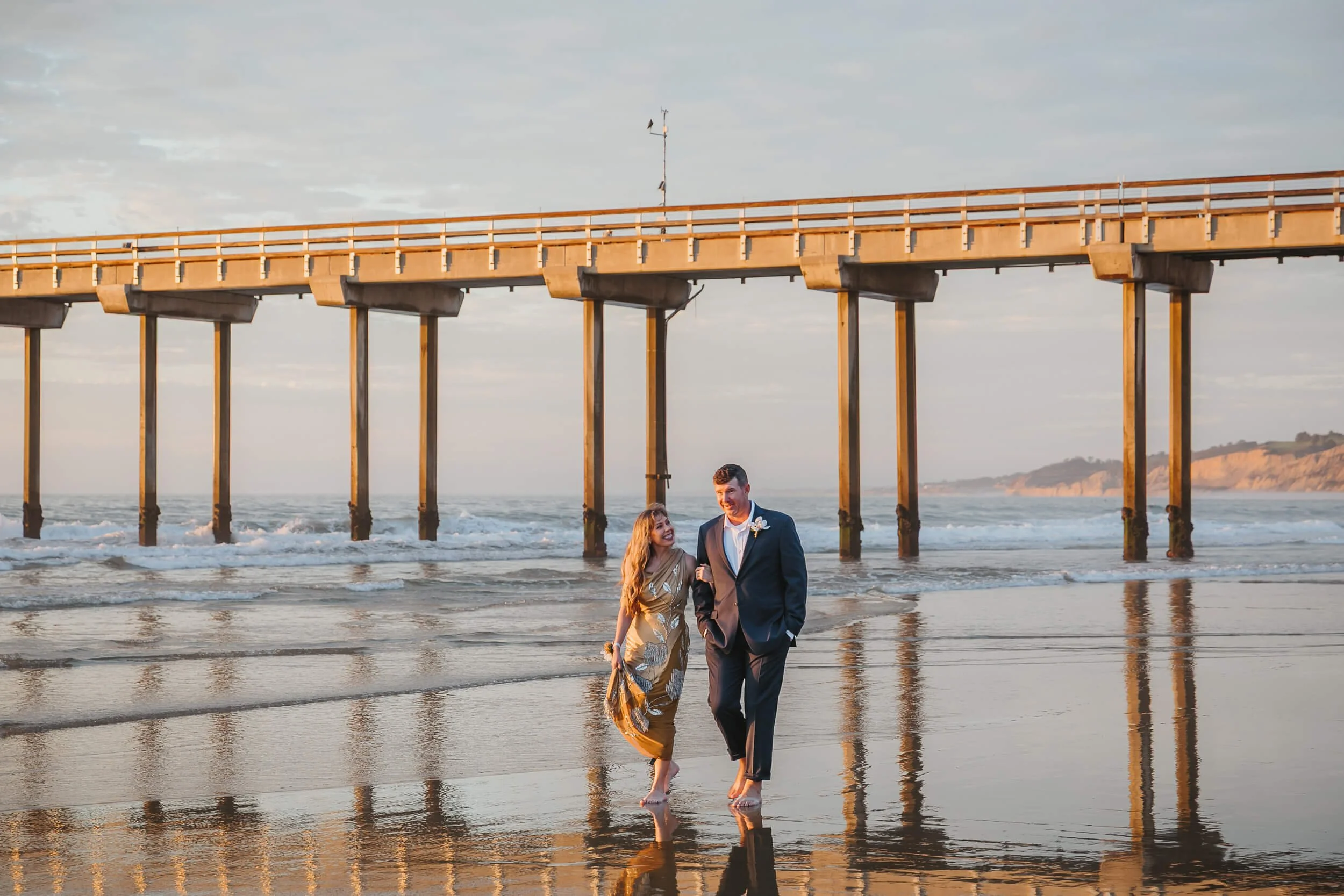 Casual and romantic shot of couple looking at each other with reflections in the sand and Scripps Pier behind