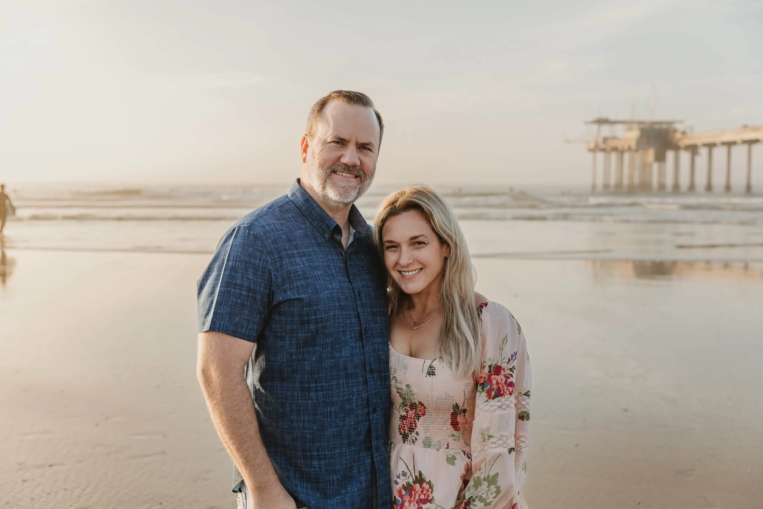 Mom and dad posing for a picture together with the ocean and Scripps Pier behind in La Jolla 