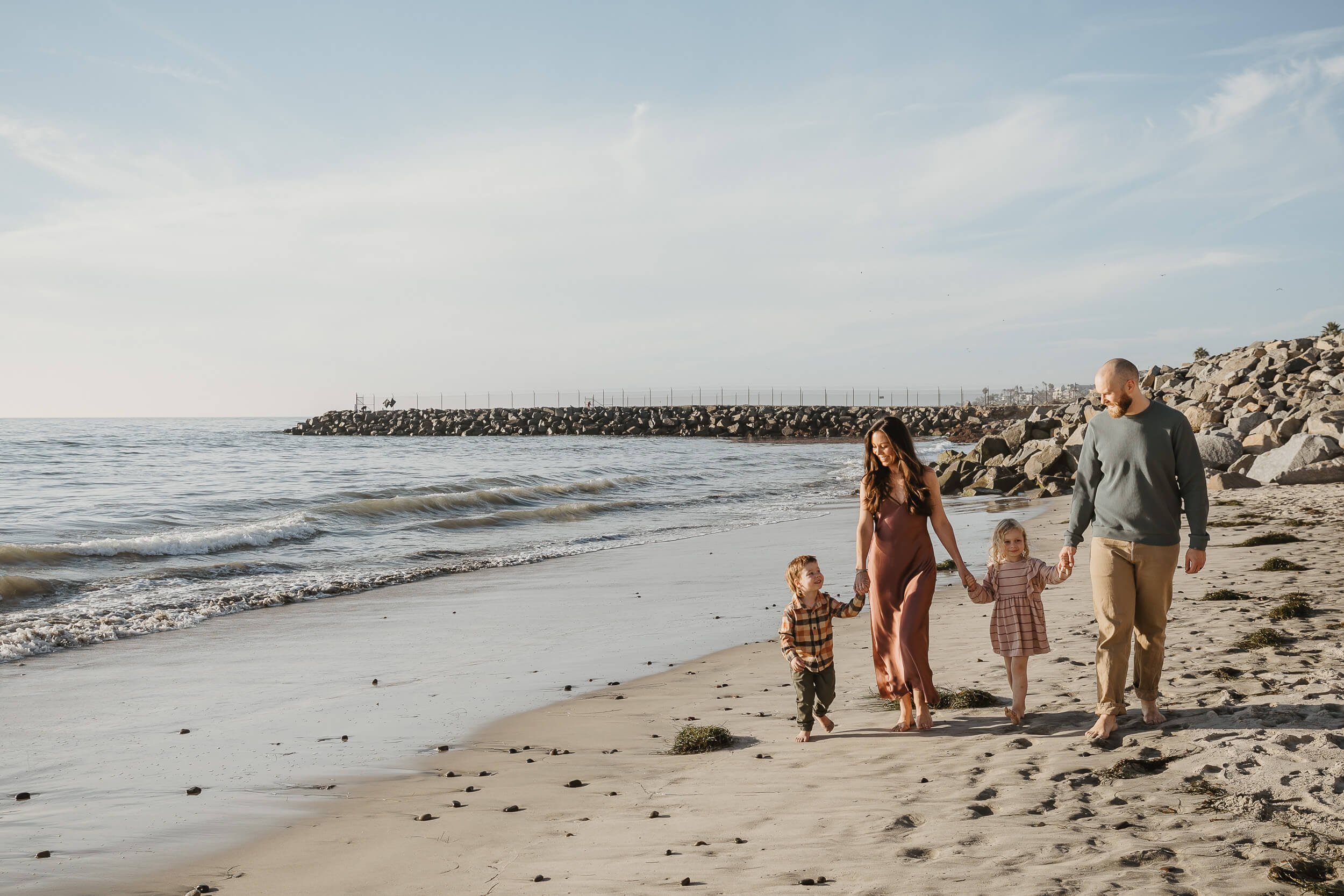 Parents walking with children along the shoreline during a Carlsbad Beach Family Photography Session in San Diego