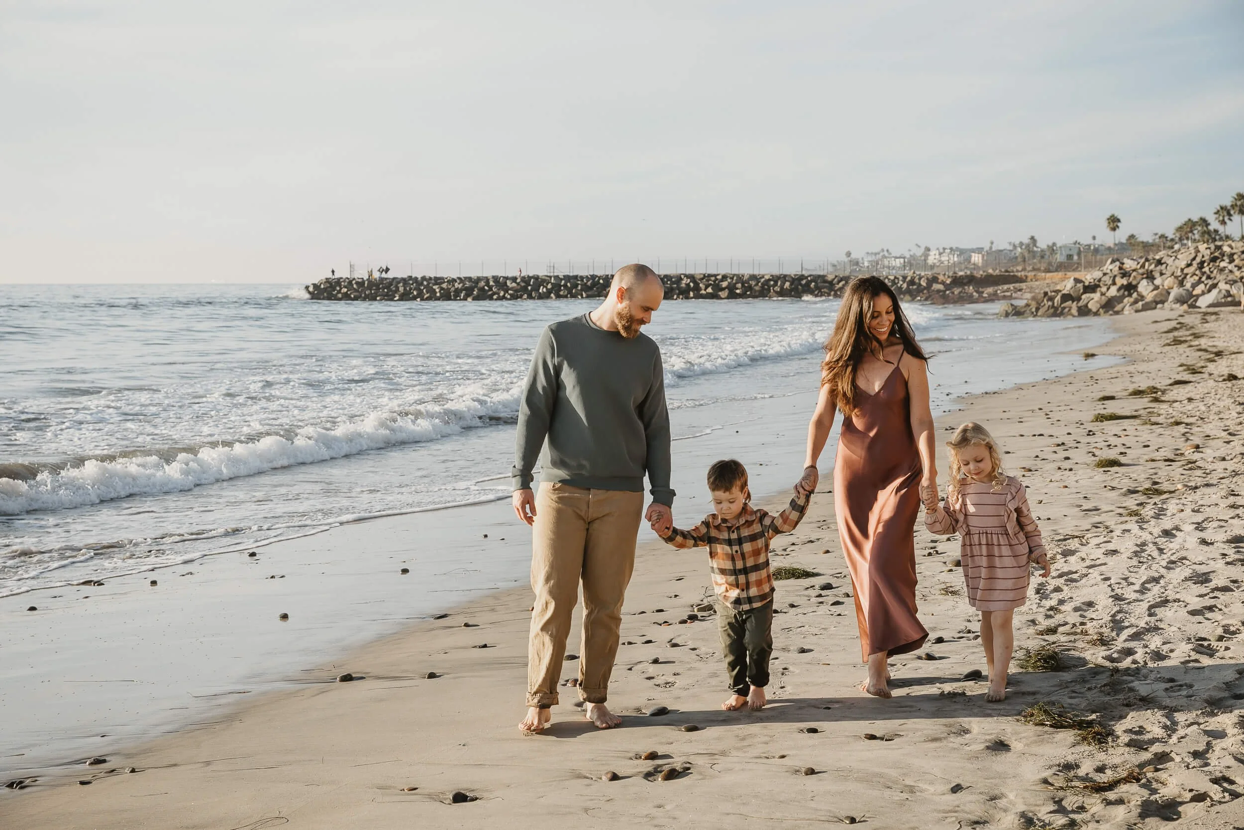 Family walking together by the ocean during golden hour in Carlsbad, California