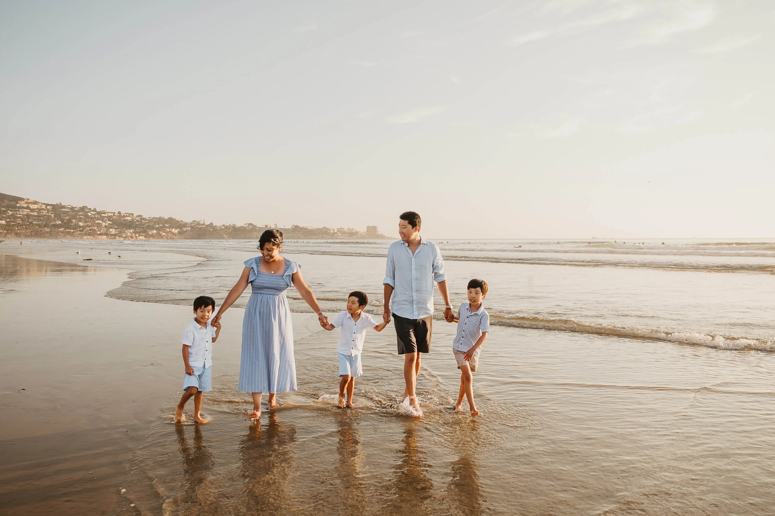 Parents and kids walking on wet sand during fall sunset in San Diego family photography session on La Jolla Shores beach