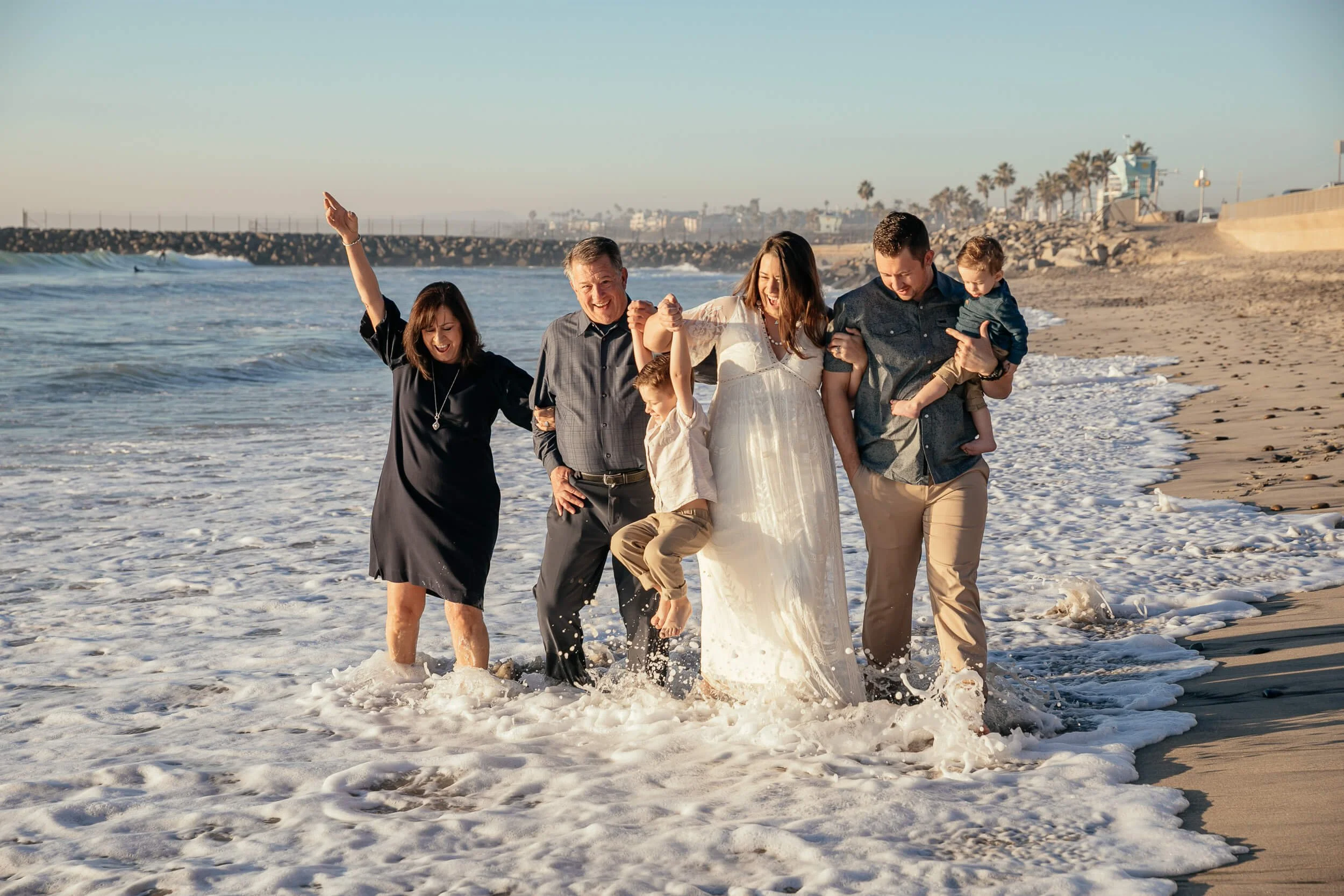 Fun beach family session with waves crashing along the shore in Carlsbad