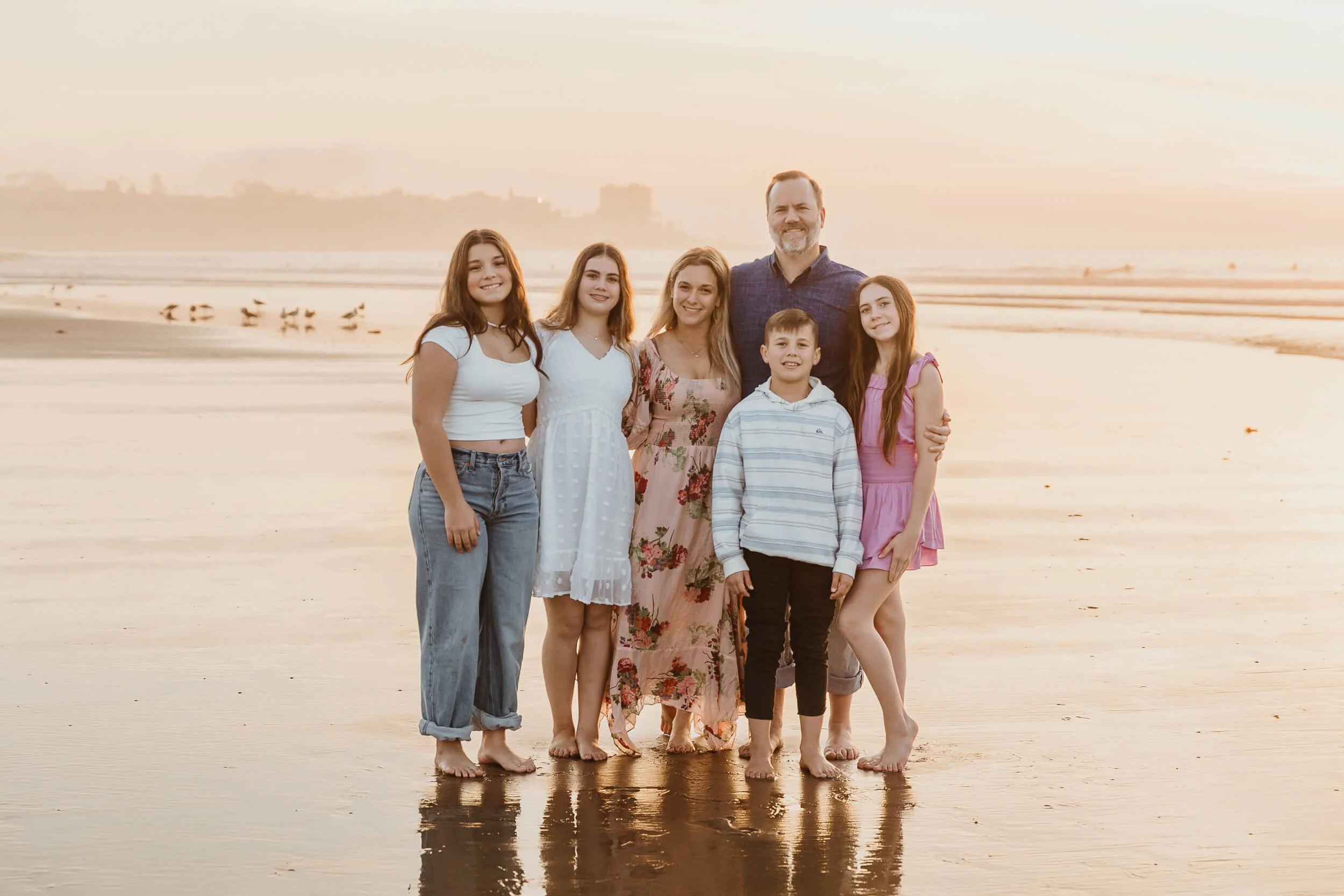 Family of six during golden hour posing for photographer during La Jolla Shores and Scripps Pier Family Photography in San Diego