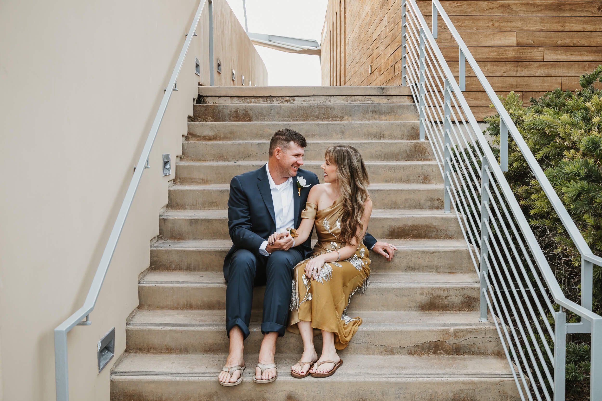 Couple looking at each other sitting on stairs at La Jolla Shores beach mini session in San Diego