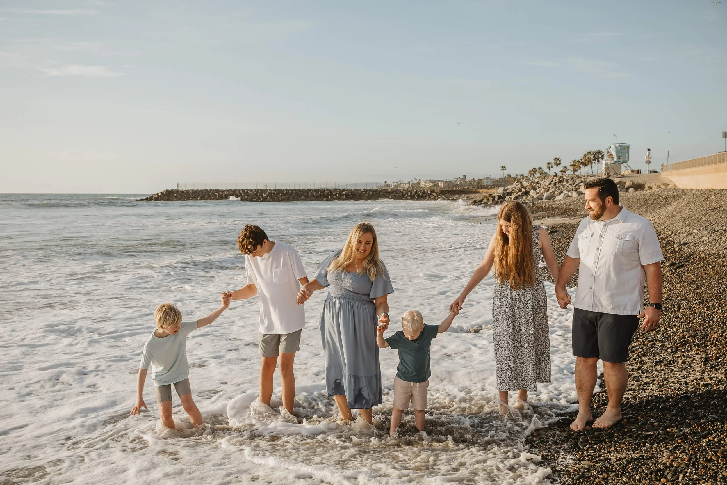 Family enjoying the waves during a sunset beach session photographed by a Carlsbad wedding photographer