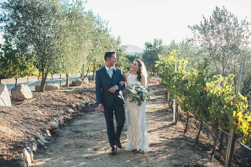 Bride and groom walking at vineyard looking at each other at Doffo winery for Temecula wedding celebration
