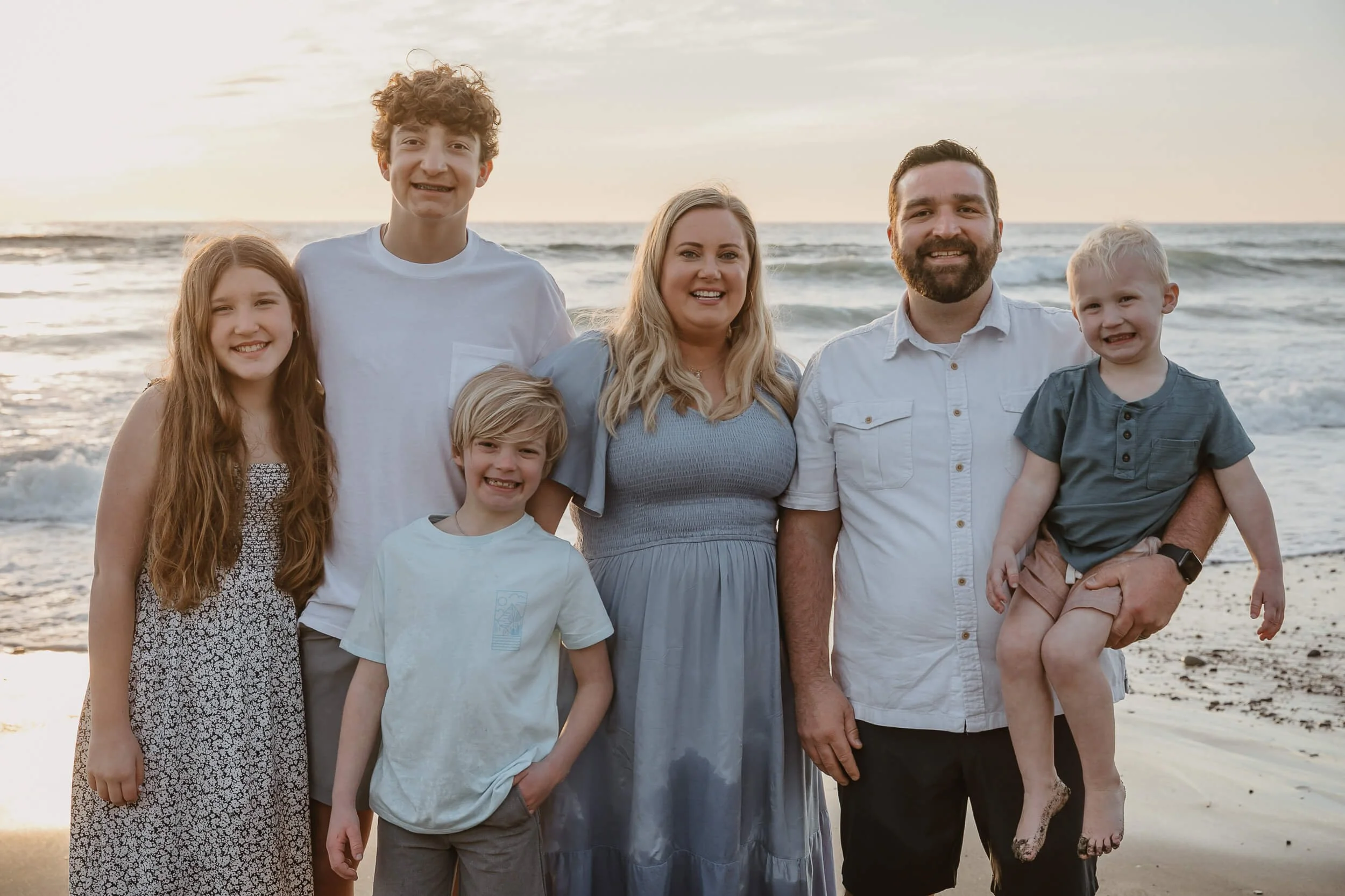 Wide family beach portrait during sunset photographed by a Carlsbad wedding photographer