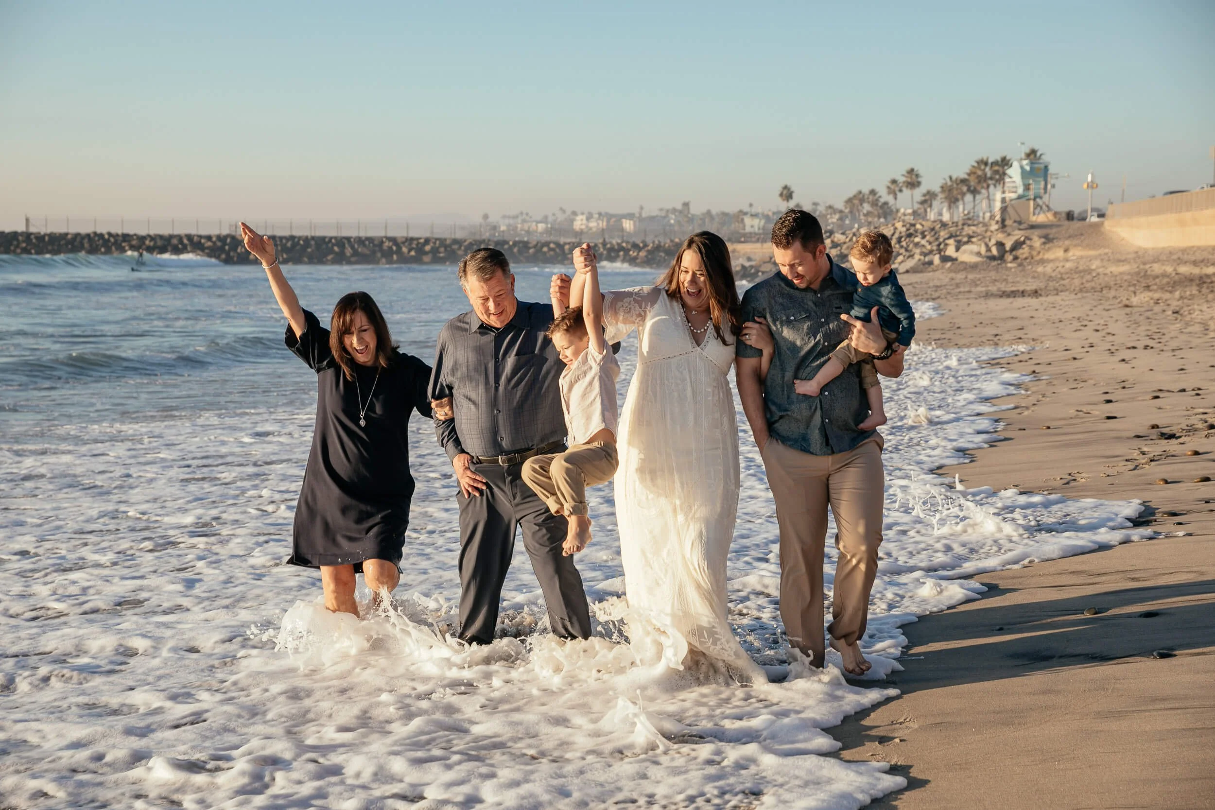 Family enjoying the ocean waves during sunset photographed by a Carlsbad wedding photographer