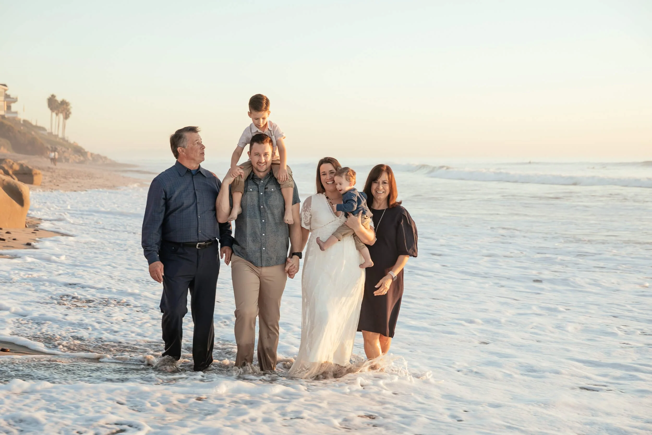 Multi generational family portrait standing in the ocean during sunset in Carlsbad
