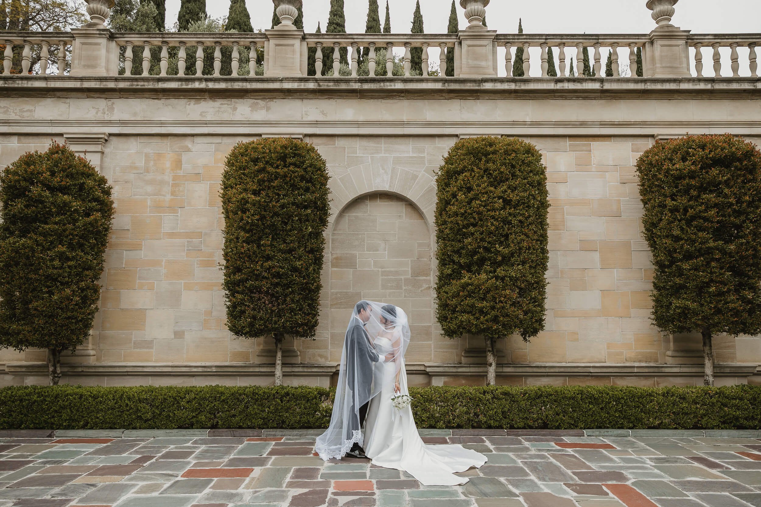 Couple looking at each other under bride veil at Greystone Mansion and Gardens Engagement Photos in Beverly Hills, Los Angeles