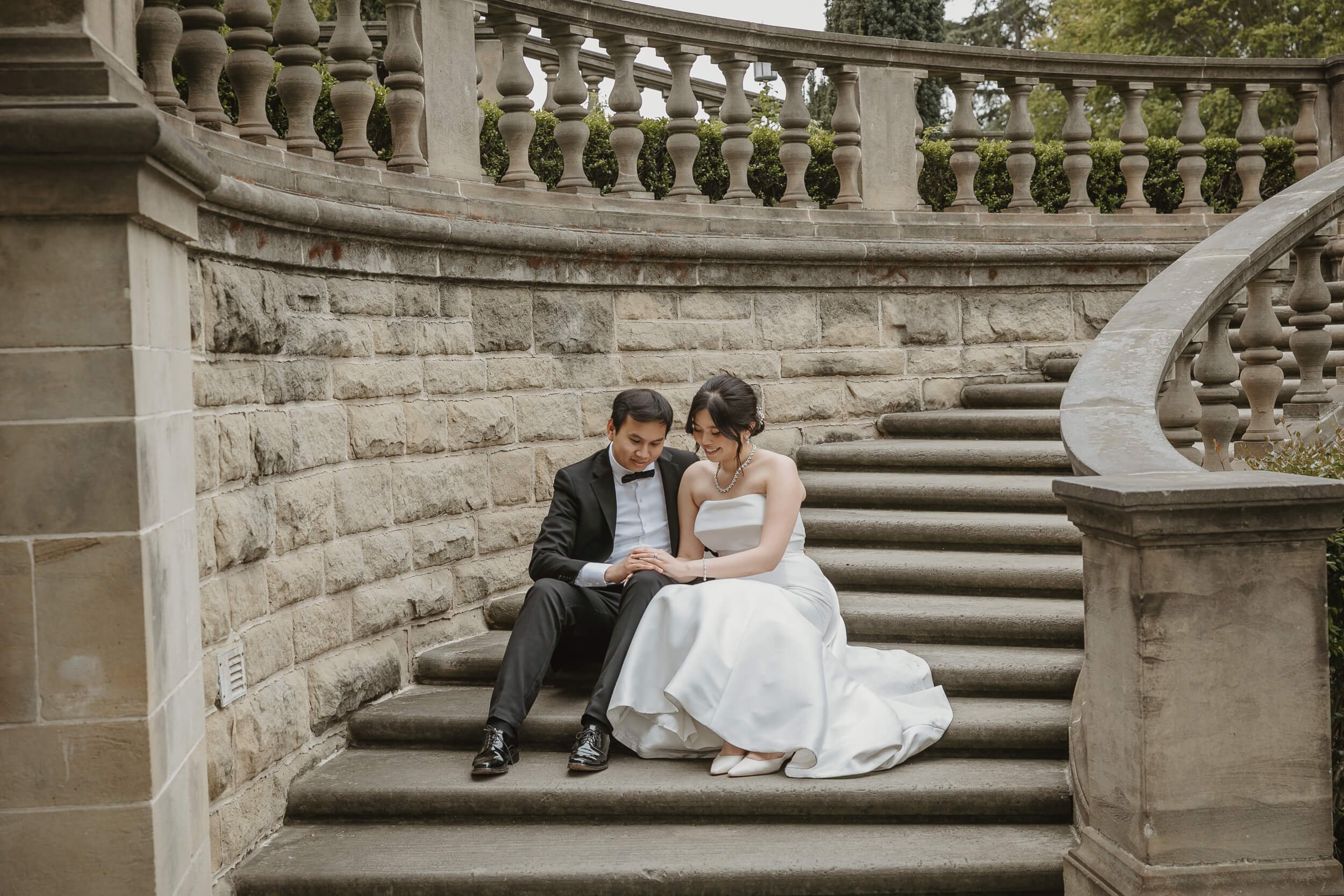 Couple looking at the rings while sitting on stairs of Greystone Mansion and Gardens Beverly Hills