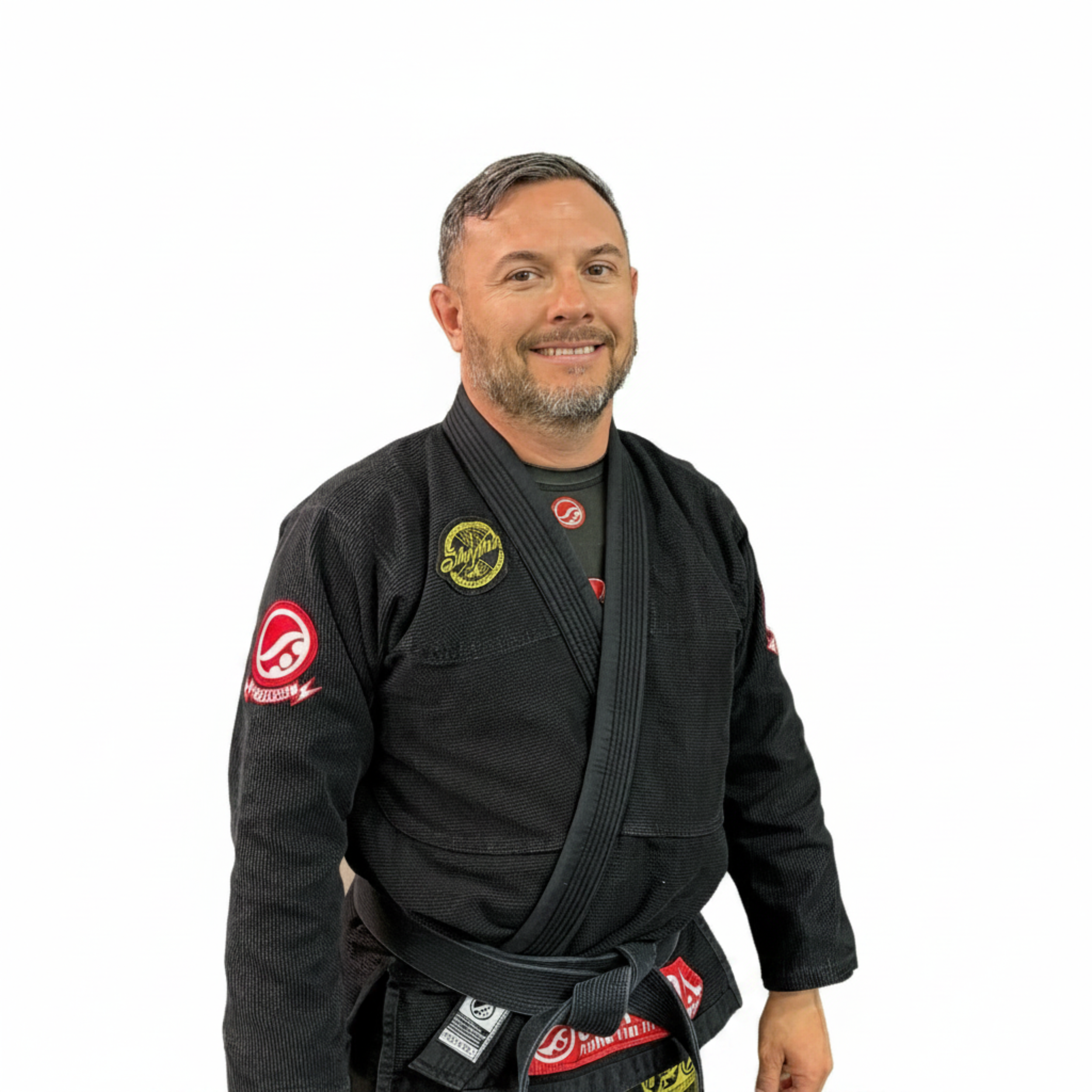 A man with short dark hair and a beard, wearing a martial arts gi, looking at the camera against a plain background.