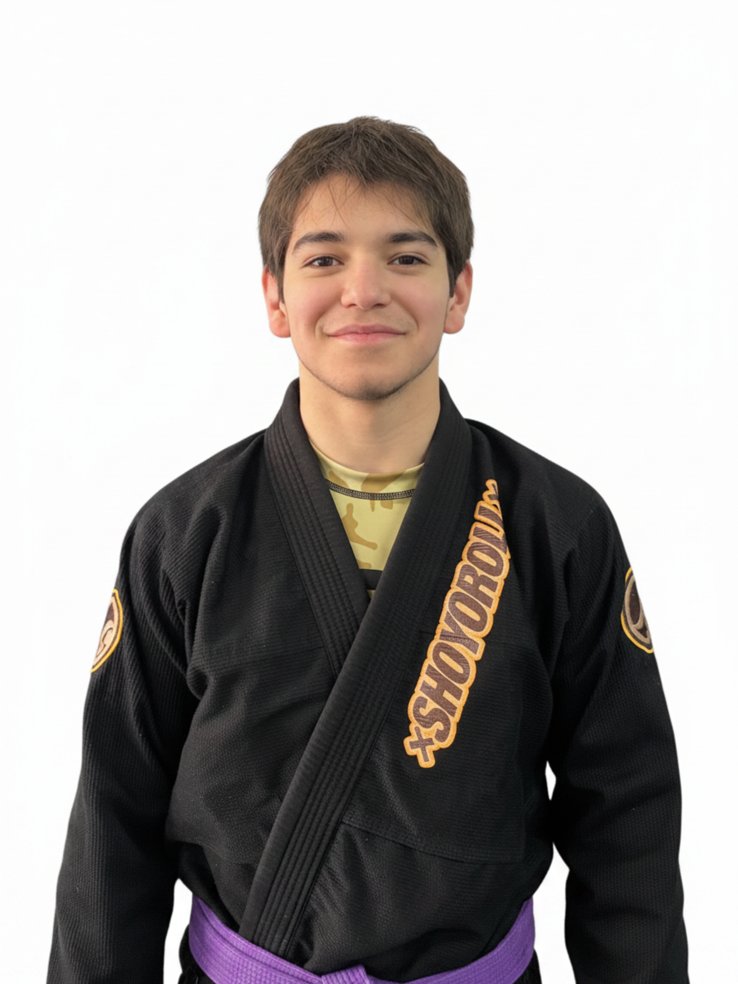 Young male martial artist in Aesudo gi with blue belt standing against a white wall.