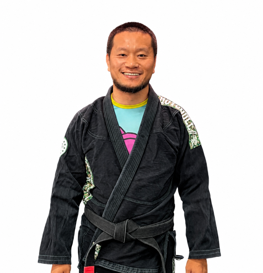 A man standing in front of a plain white wall, wearing a beige shirt with a dragon design and the text 'I'm Fine'.