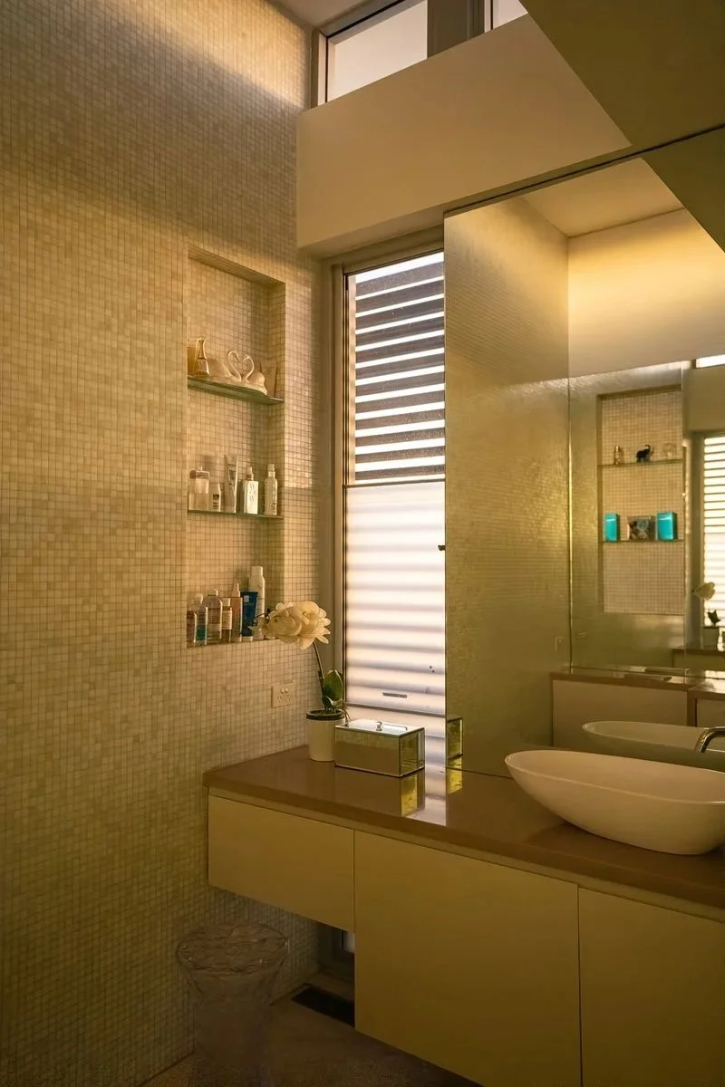 Main bathroom simple clean tiles and marble vanity. Showcasing tall narrow window, a shower area with glass partition. Designed by Scalabrino Architecture.