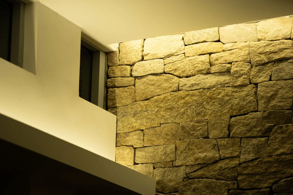 Interior view showing a stone accent wall with warm lighting, part of a modern building interior.