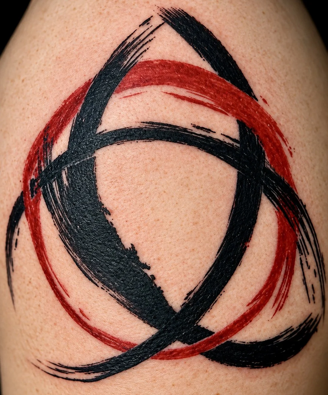 Abstract tattoo with black and red brushstroke circles and lines on skin.