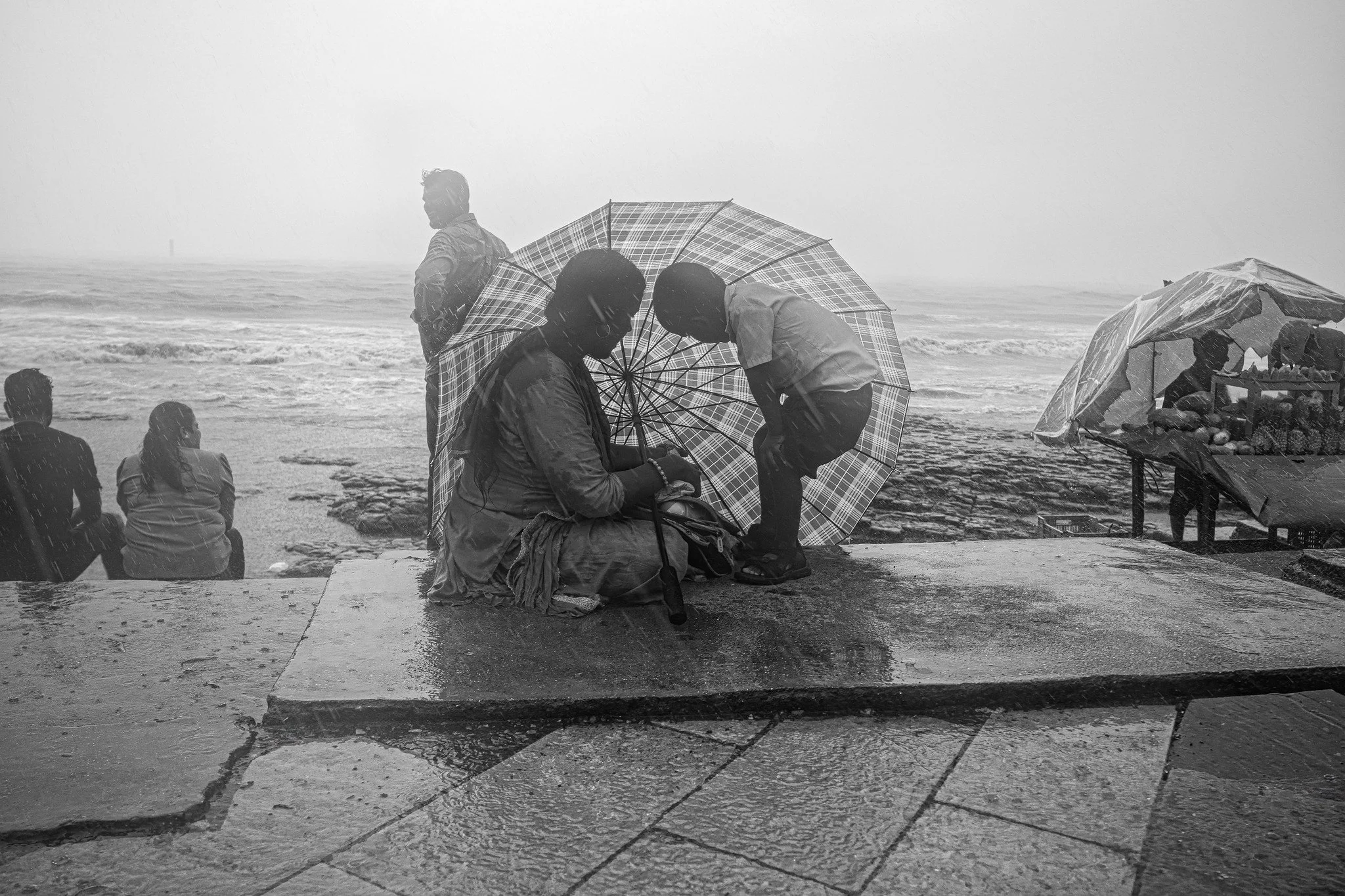 Mother and child seeking shelter in an umbrella during monsoon in Mumbai.