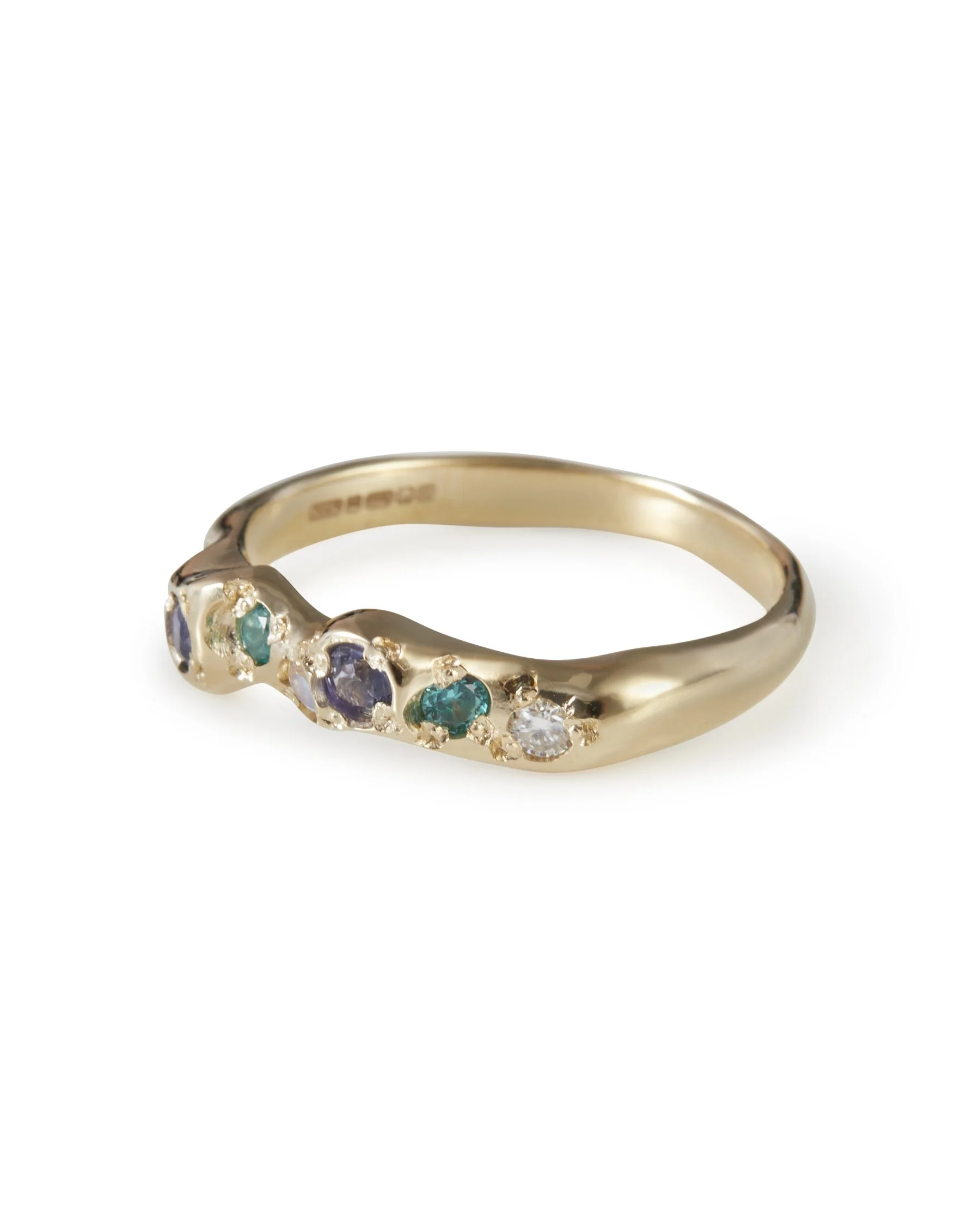 Angled view of the Mermaid Mini Band, a 9ct yellow gold ring set with purple sapphires, paraiba YAG, moonstone and moissanite.